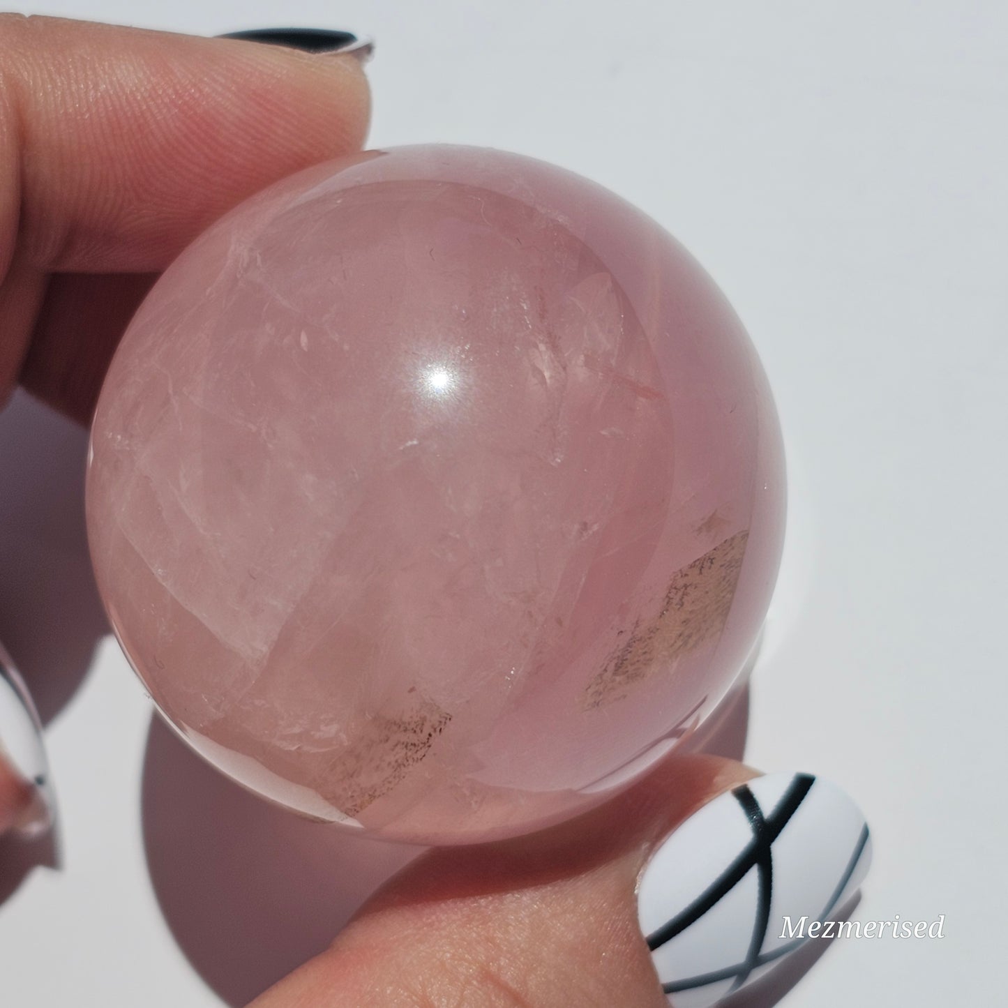 A stunning Rose Quartz sphere with asterism, beautiful rainbows, and gorgeous dendritic inclusions