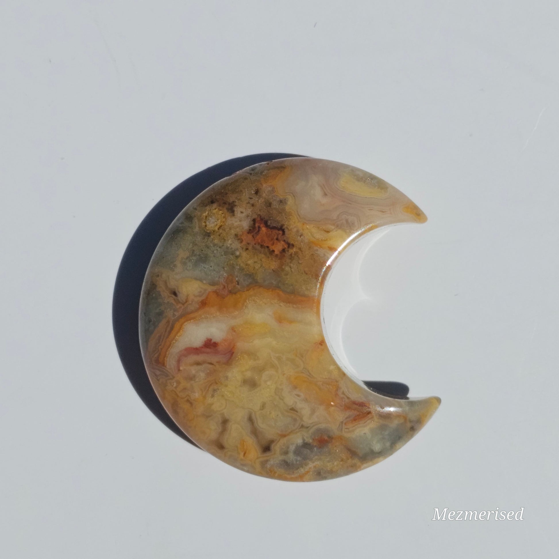 A small Crazy Lace Agate crescent with mesmerising patterns.