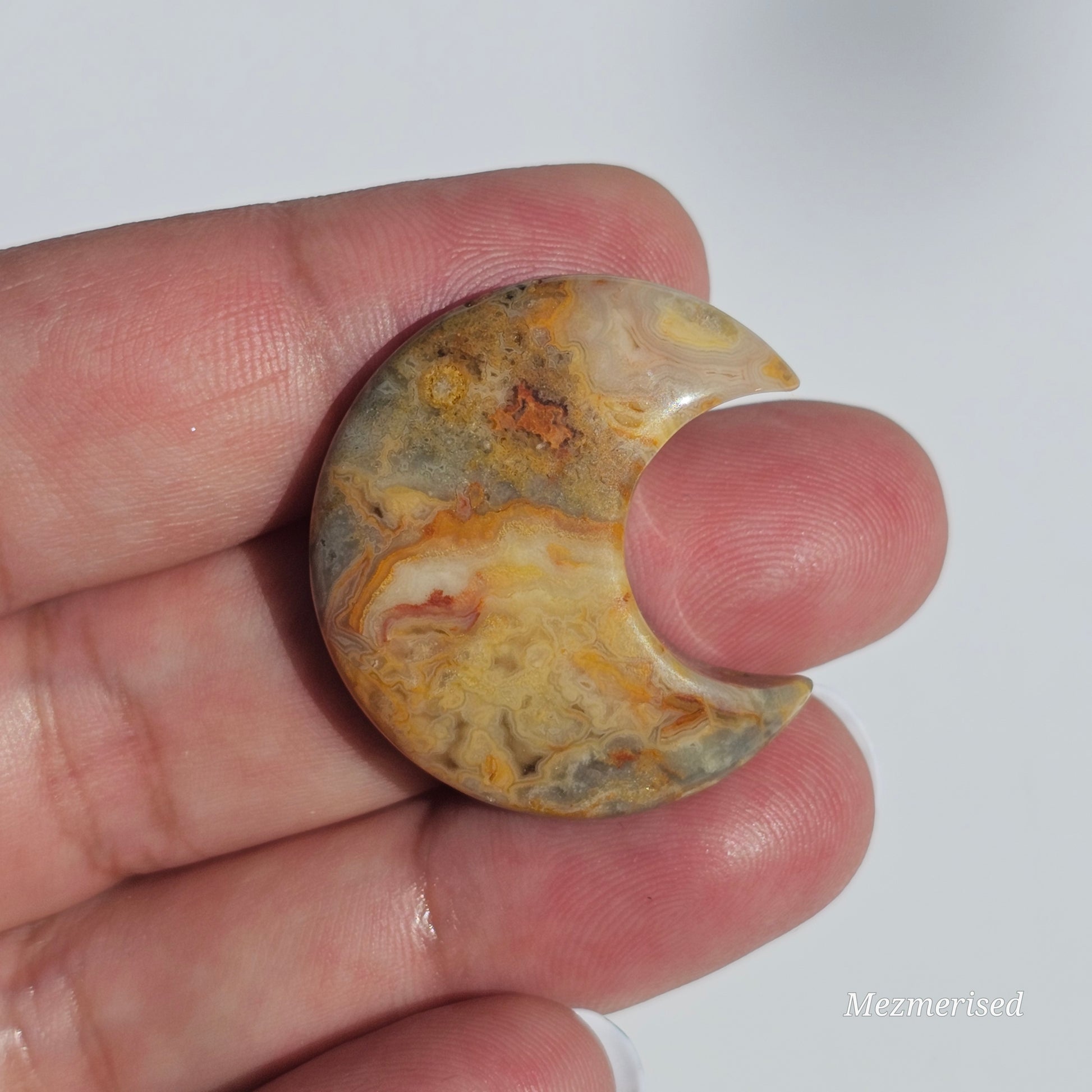 A small Crazy Lace Agate crescent with mesmerising patterns.