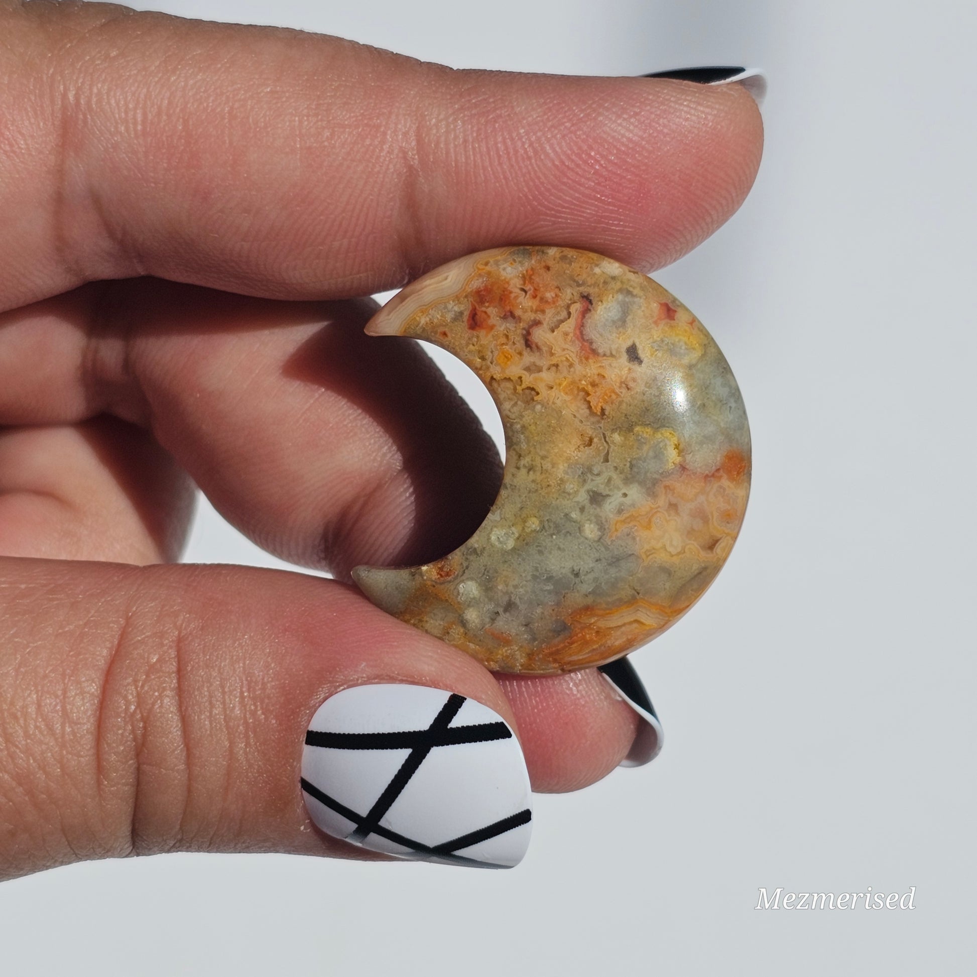 A small Crazy Lace Agate crescent with mesmerising patterns.