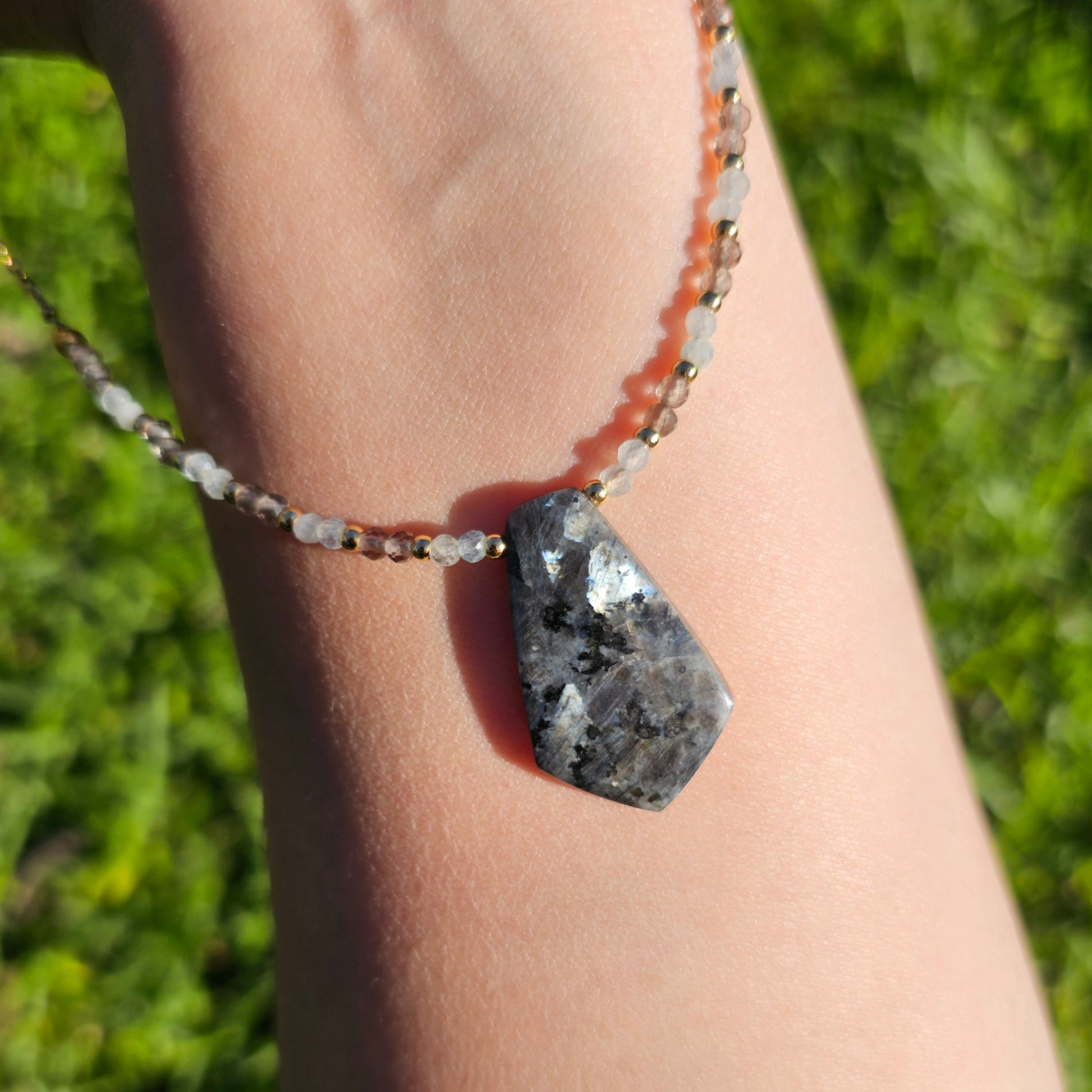 Lunar bloom is a focal Larvikite pendant necklace adorned with Smoky Quartz and Aquamarine beads.