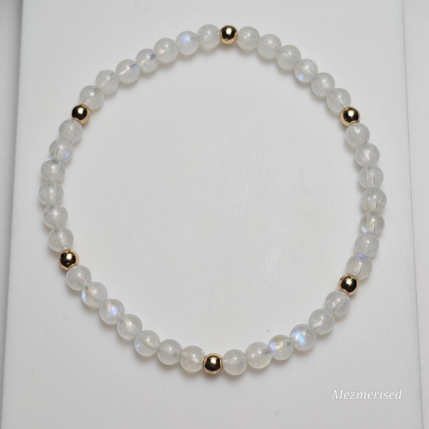 Minimal 4mm AA Grade Rainbow Moonstone bracelet with gold accents styled in flat lay display.