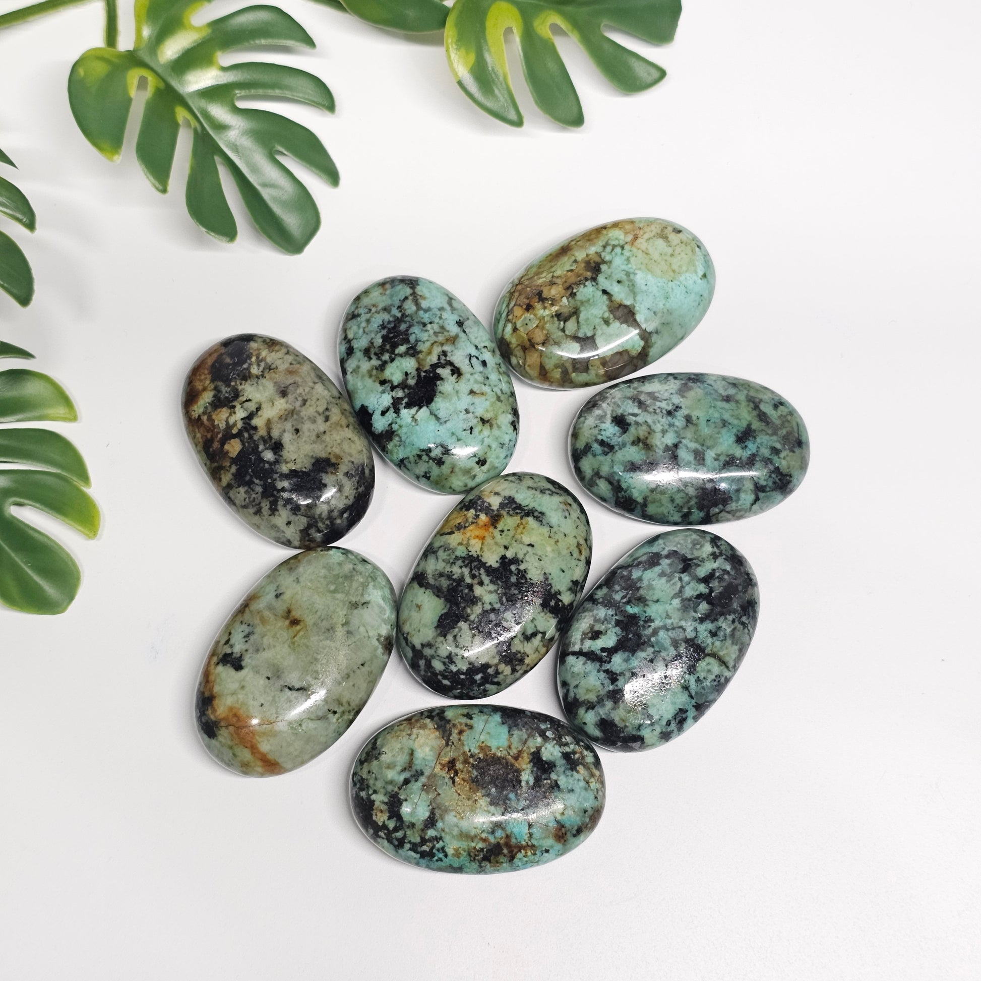 Polished African Turquoise palm stones displayed on a flat surface, showcasing their natural colours, unique patterns, and individual character.
