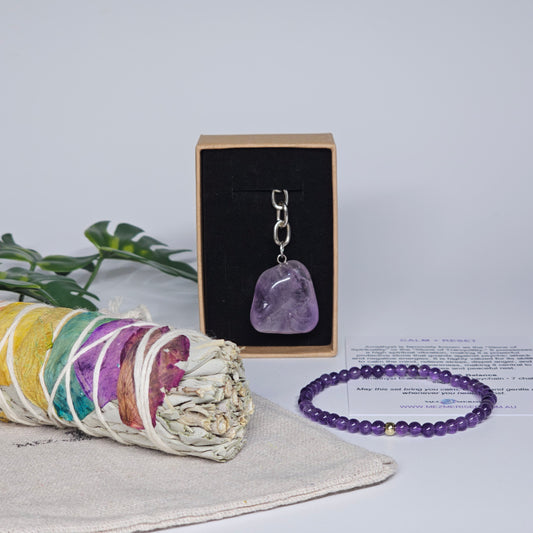 Amethyst keychain and bracelet with sage stick styled on pouch inside crystal gift set box.