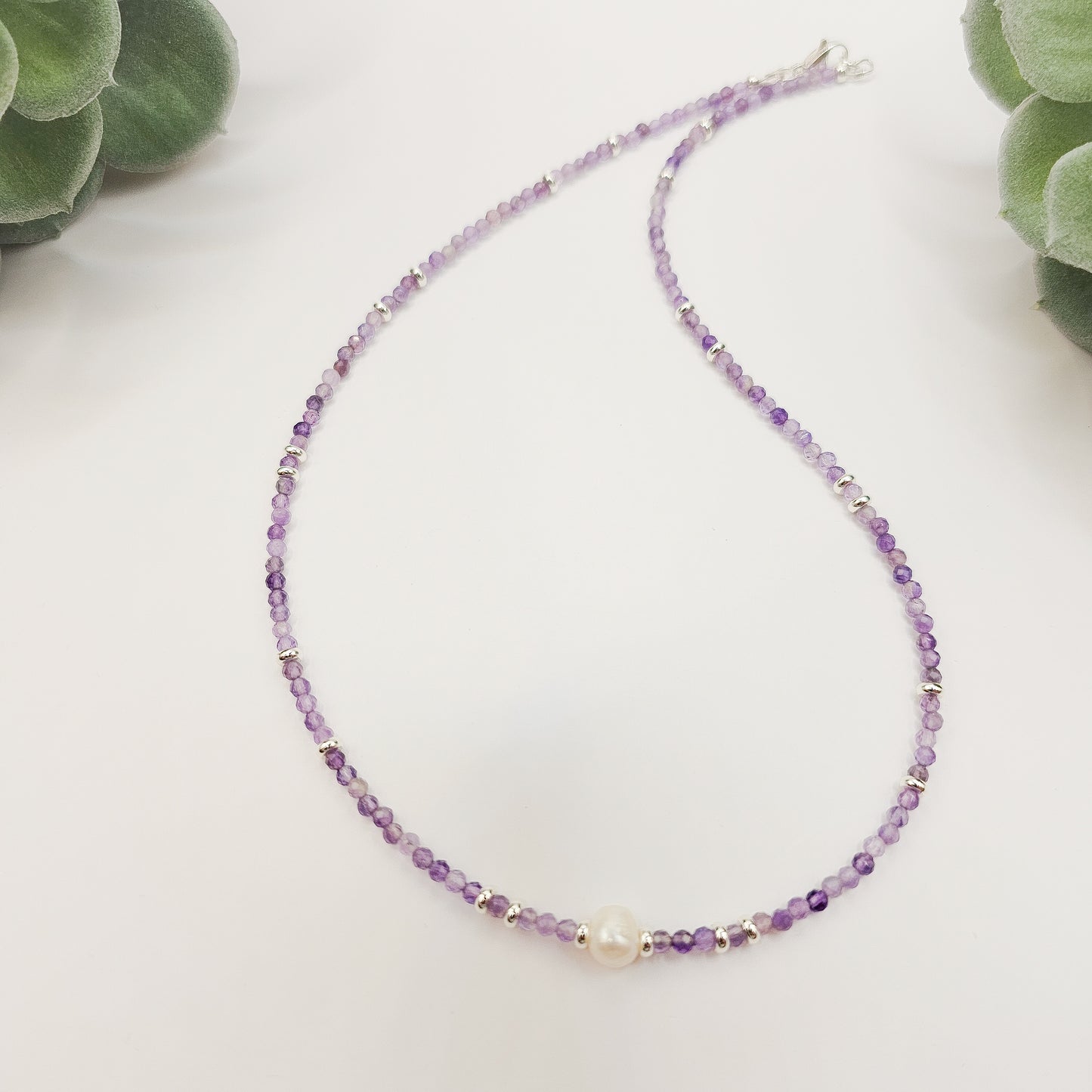 Amethyst and pearl necklace laid flat.