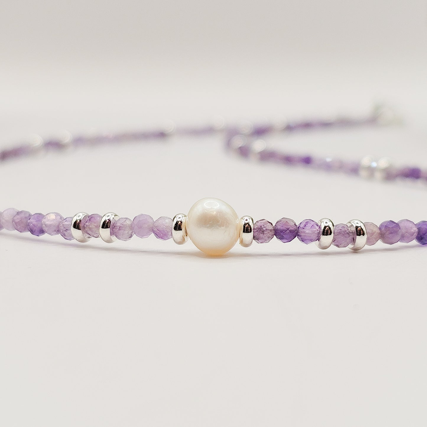 Flat close-up angle view of Amethyst pearl necklace laid down.