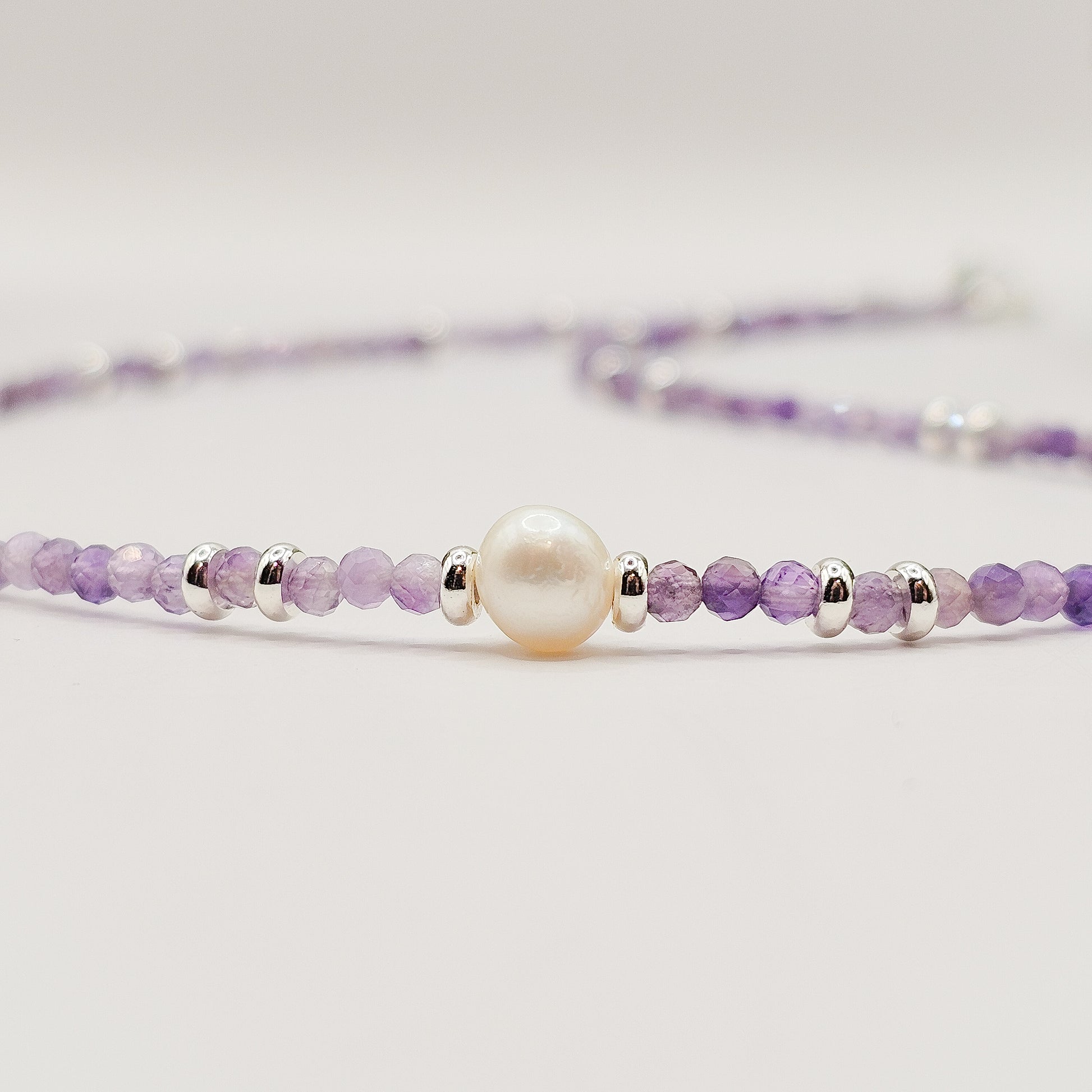Flat close-up angle view of Amethyst pearl necklace laid down.