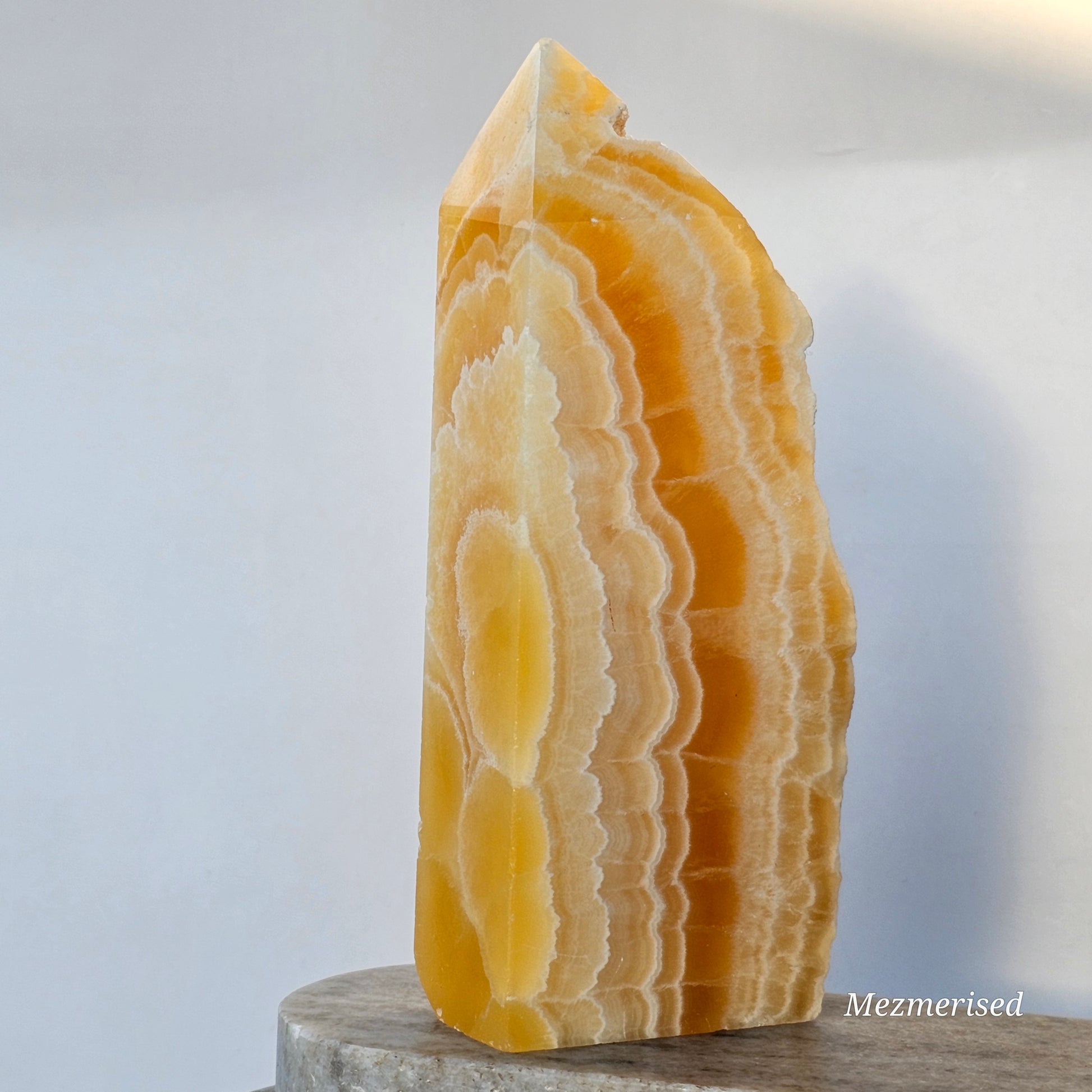 The reverse side of the calcite tower showcasing natural geological patterns and vibrant, sun-kissed citrus hues.