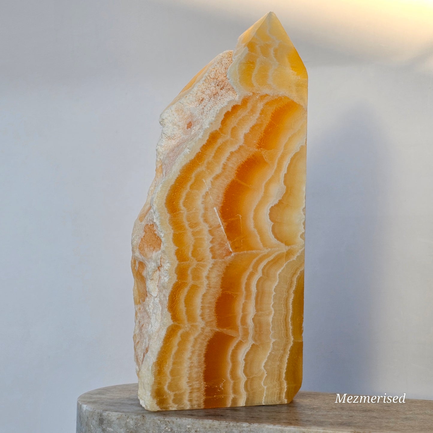 A vertical profile of the calcite point highlighting the transition from translucent orange layers to opaque white banding.