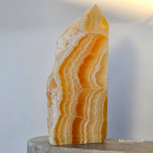 A vertical profile of the calcite point highlighting the transition from translucent orange layers to opaque white banding.