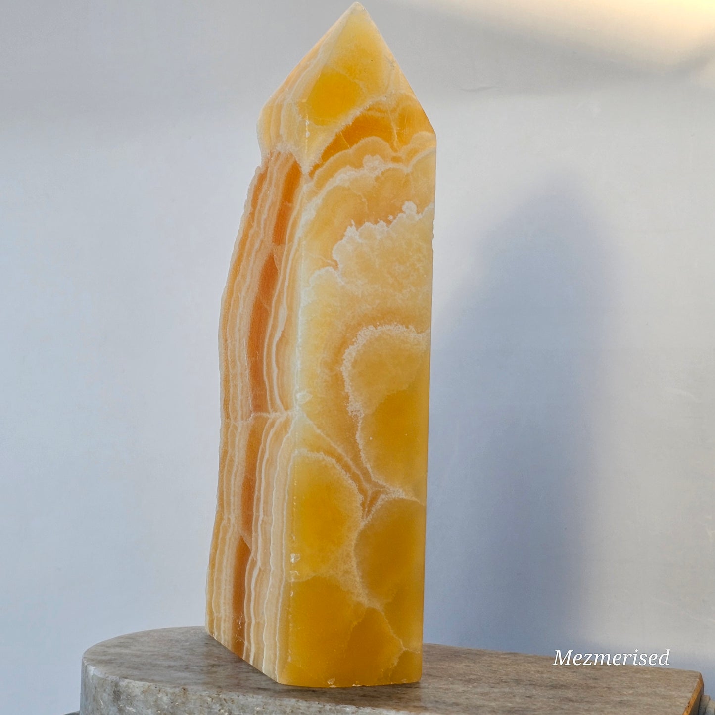 The reverse side of the calcite tower showcasing natural geological patterns and vibrant, sun-kissed citrus hues.