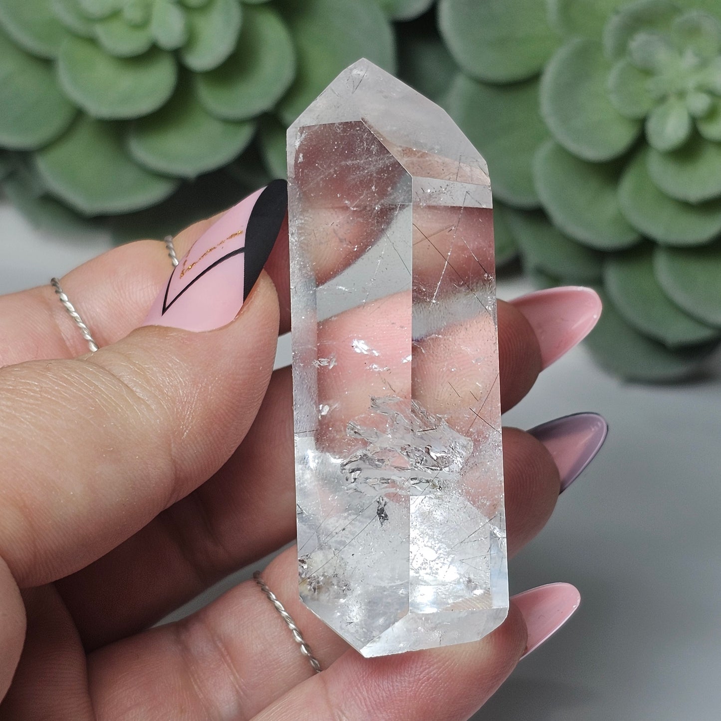 Black Rutile Quartz tower held in hand, highlighting its clarity, size, and unique angled display shape.
