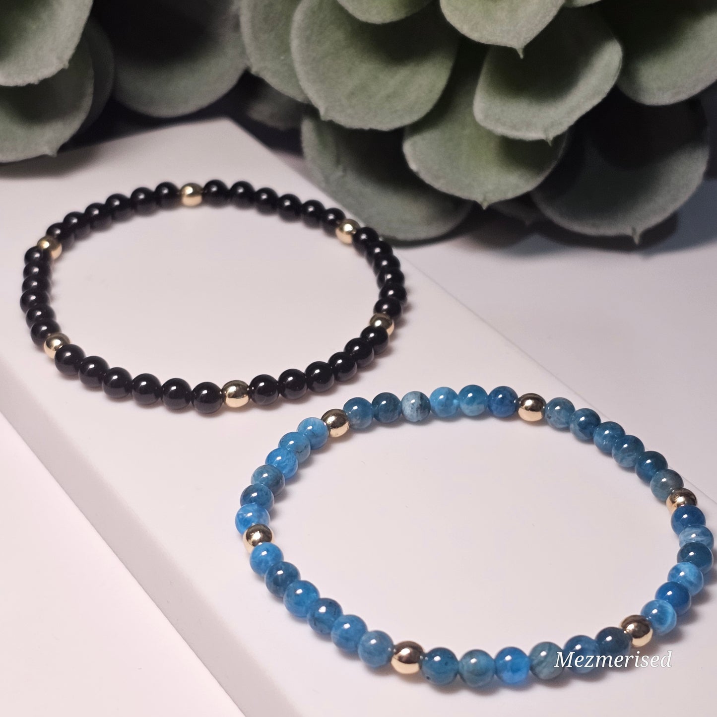Minimal 4mm Black Tourmaline and Blue Apatite bracelets with gold accents styled in flat lay display.