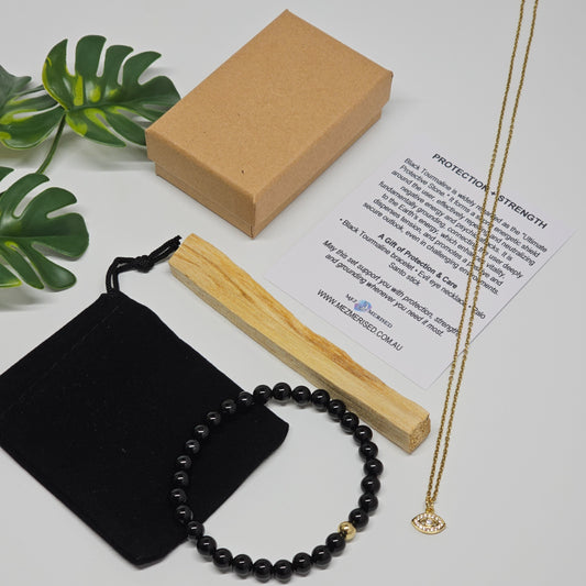 Black Tourmaline bracelet, evil eye necklace and Palo Santo set displayed with velvet pouch, gift box and information card.