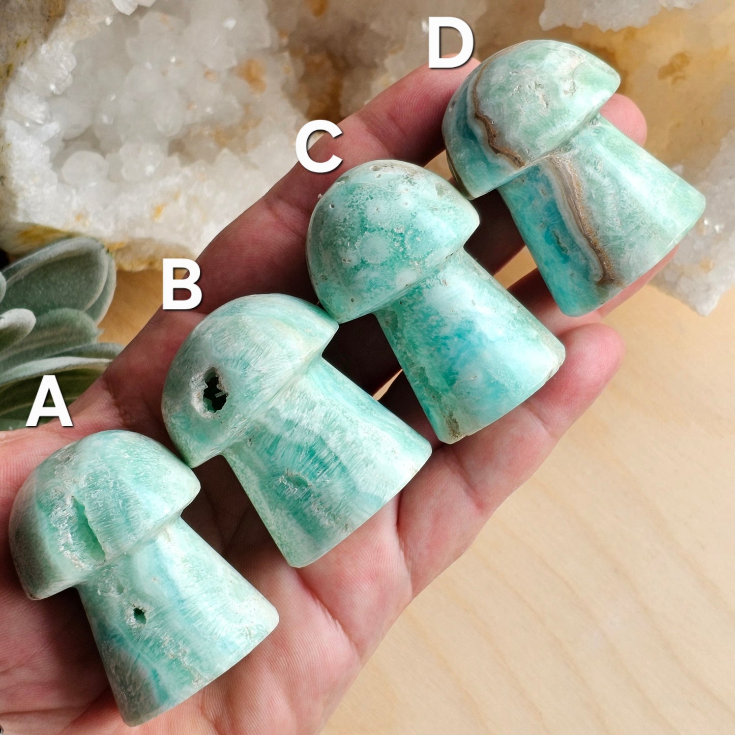 Blue Aragonite mushroom carvings held in hand to show size and detail, highlighting smooth polished surfaces and natural calming blue tones.