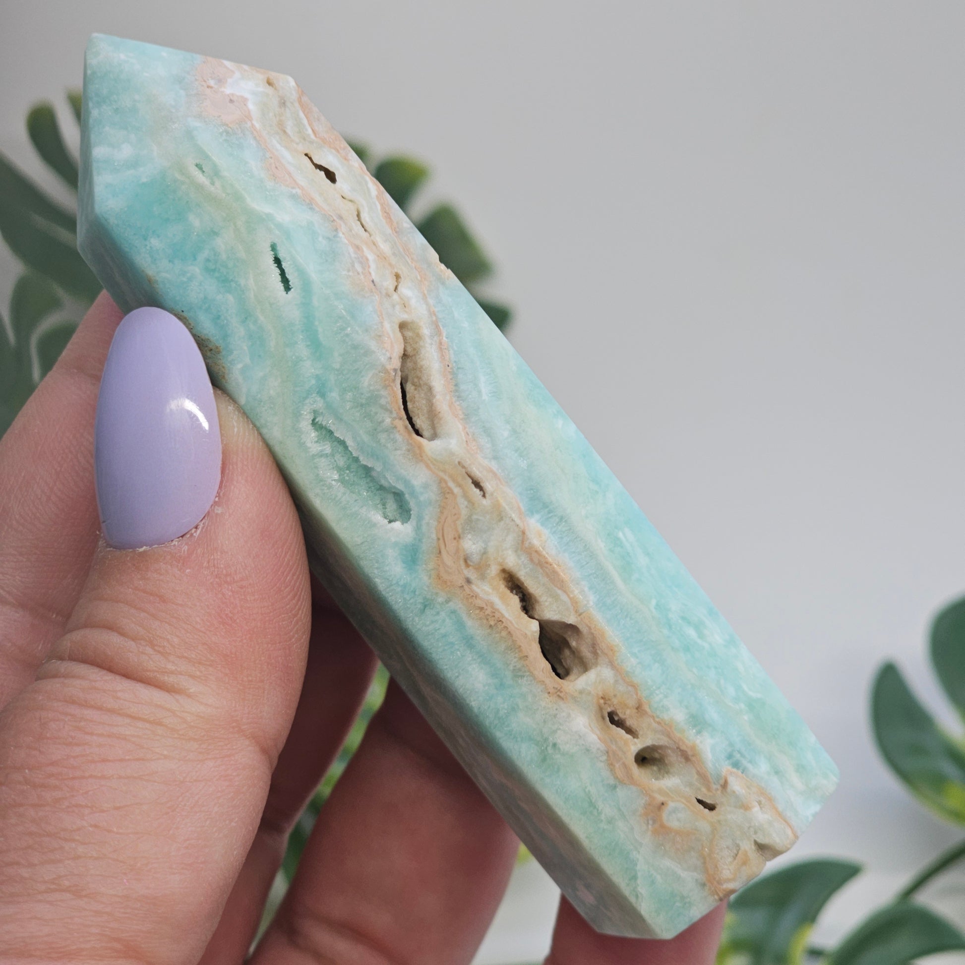 Blue Aragonite tower held in hand to show size, natural pockets, and druzy features.