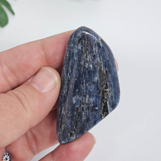 Close up of Blue Kyanite polished freeform in hand, highlighting natural variation, colour depth, and crystal structure
