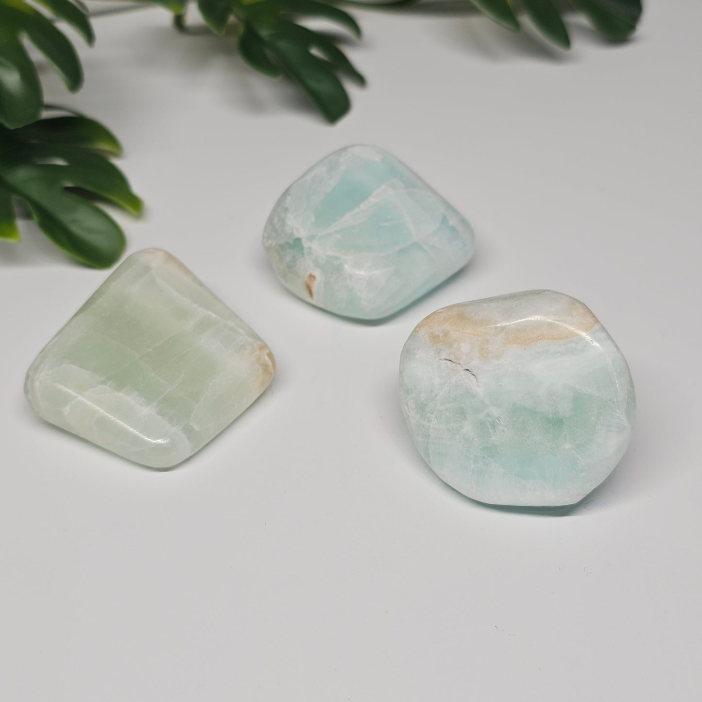 Large Caribbean Calcite tumble stones arranged on a flat surface, displaying stronger colour saturation, clarity, and pattern definition.