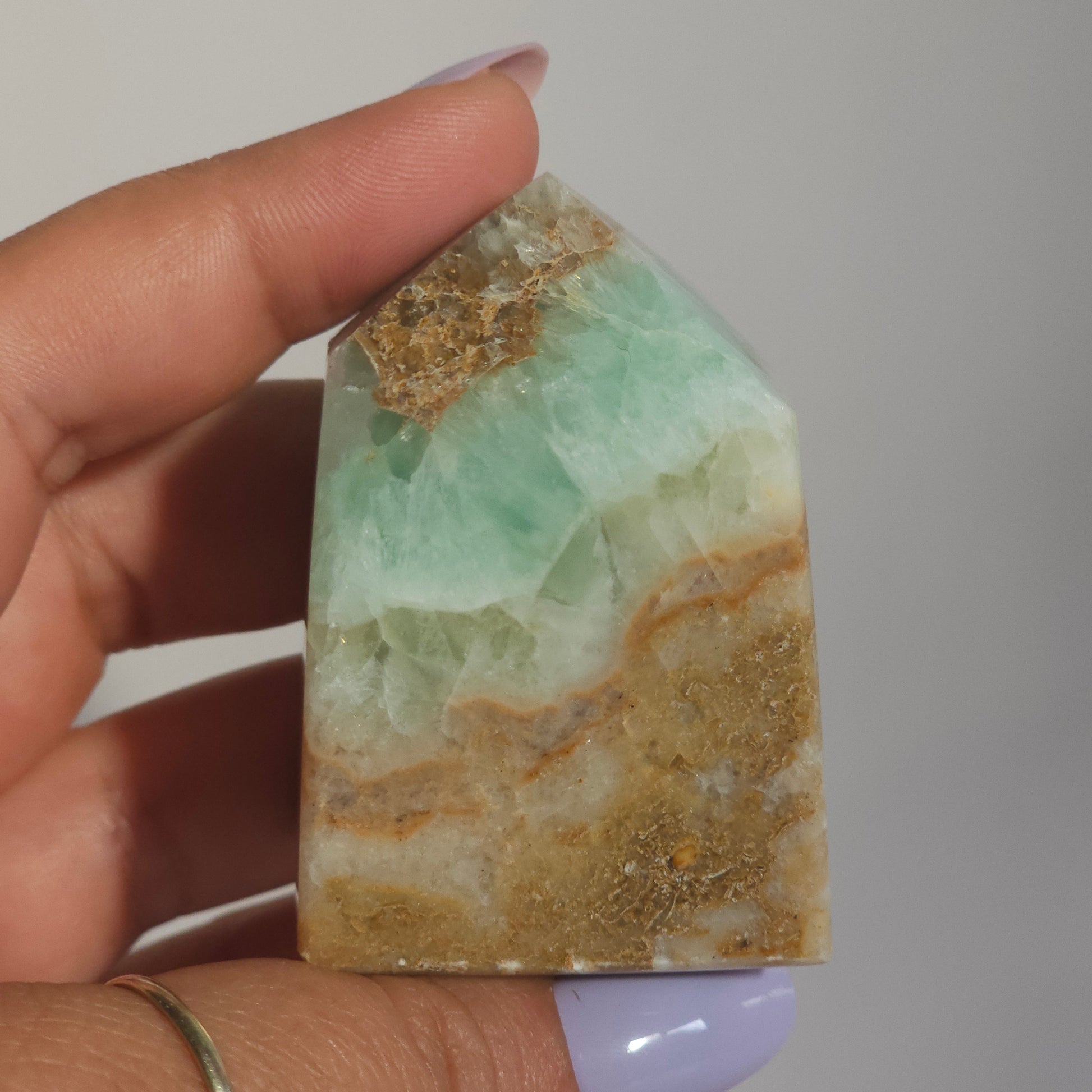Caribbean Calcite Tower In Hand Close Up Highlighting Coastal Green Tones and Texture