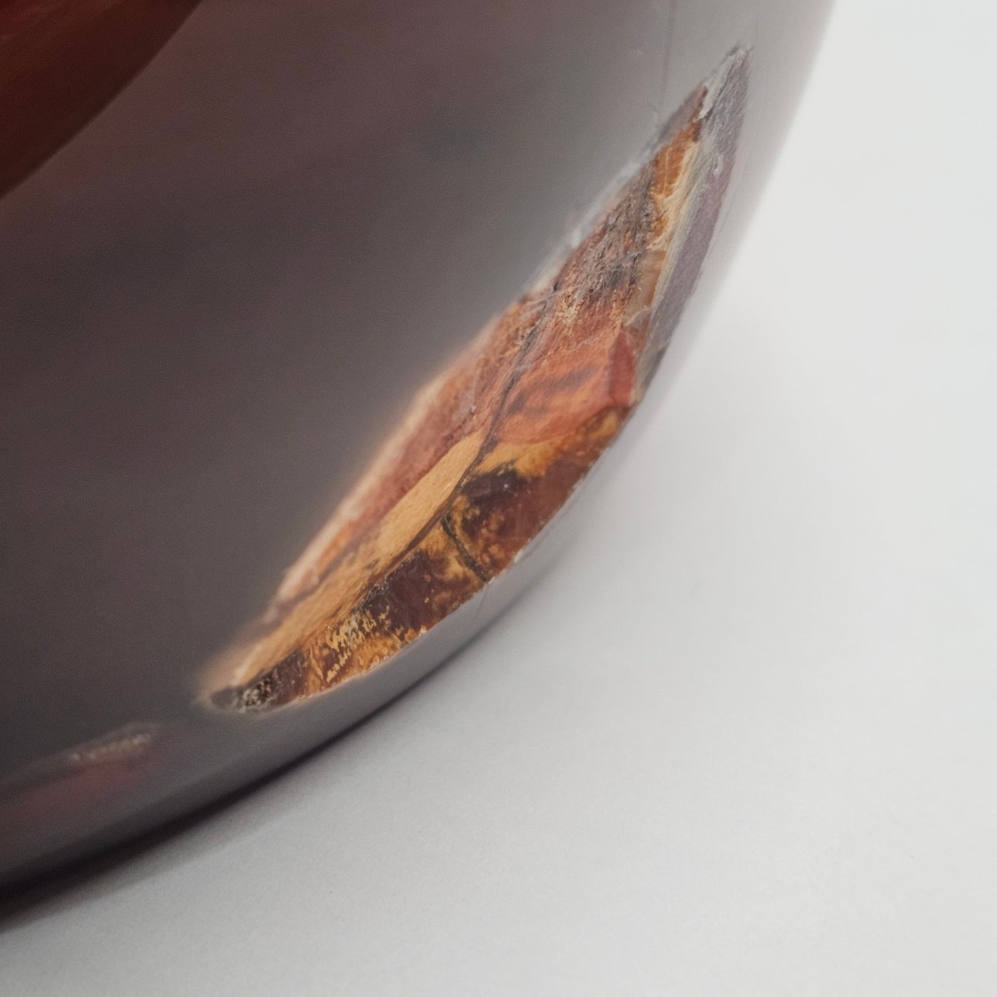 Side angle of the dark Carnelian crystal bowl highlighting the large natural indentation on the outer wall, along with the rich warm colouring and polished Madagascan Carnelian surface.