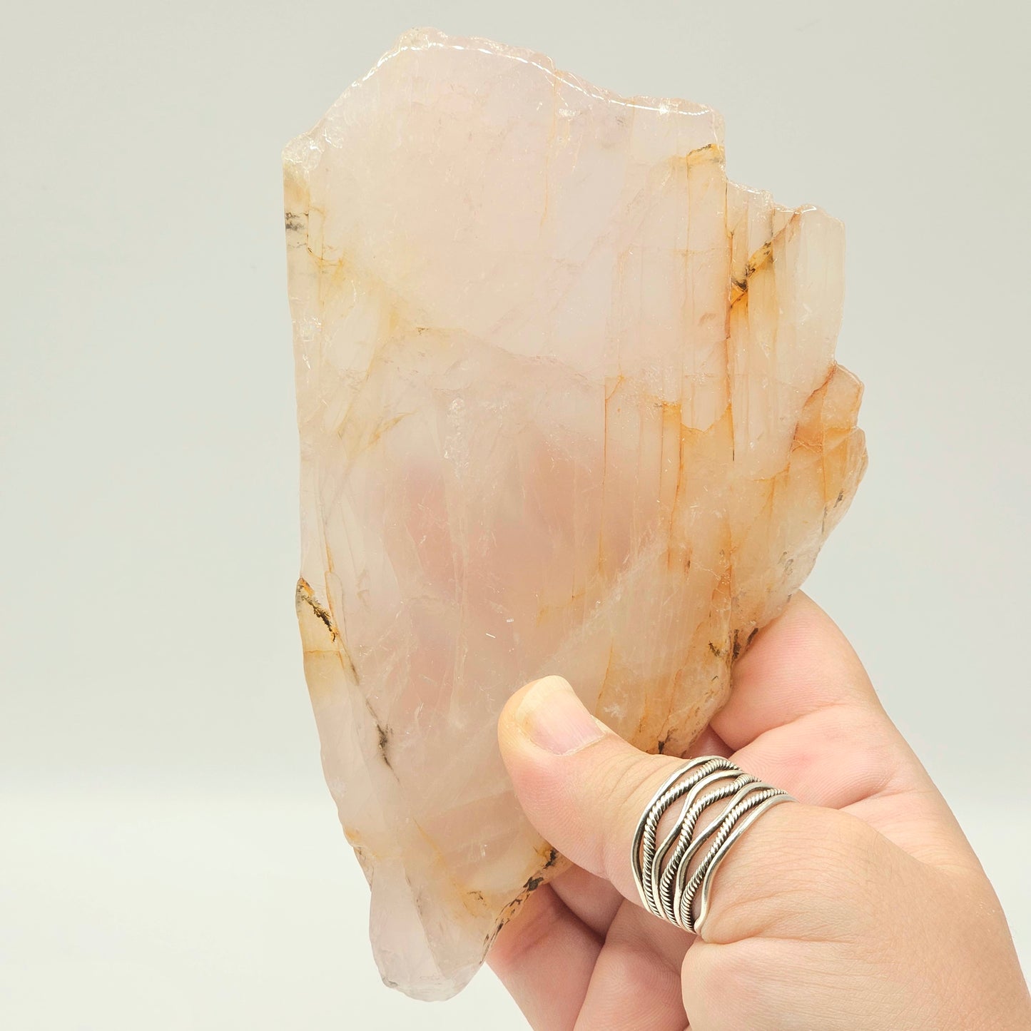 Translucent Dendritic Rose Quartz slab held in hand under studio lighting, revealing natural depth, polished finish, and delicate internal inclusions.