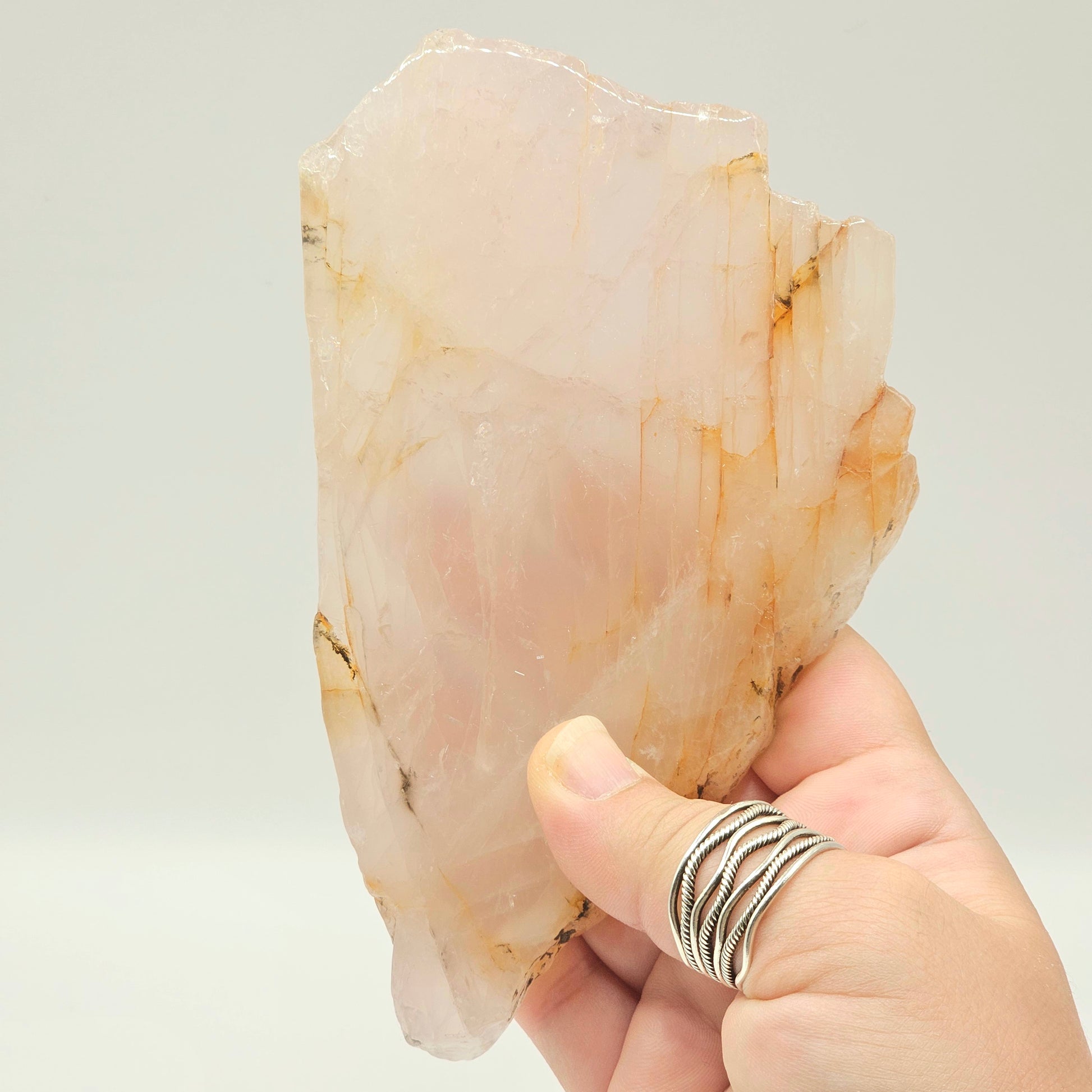 Translucent Dendritic Rose Quartz slab held in hand under studio lighting, revealing natural depth, polished finish, and delicate internal inclusions.