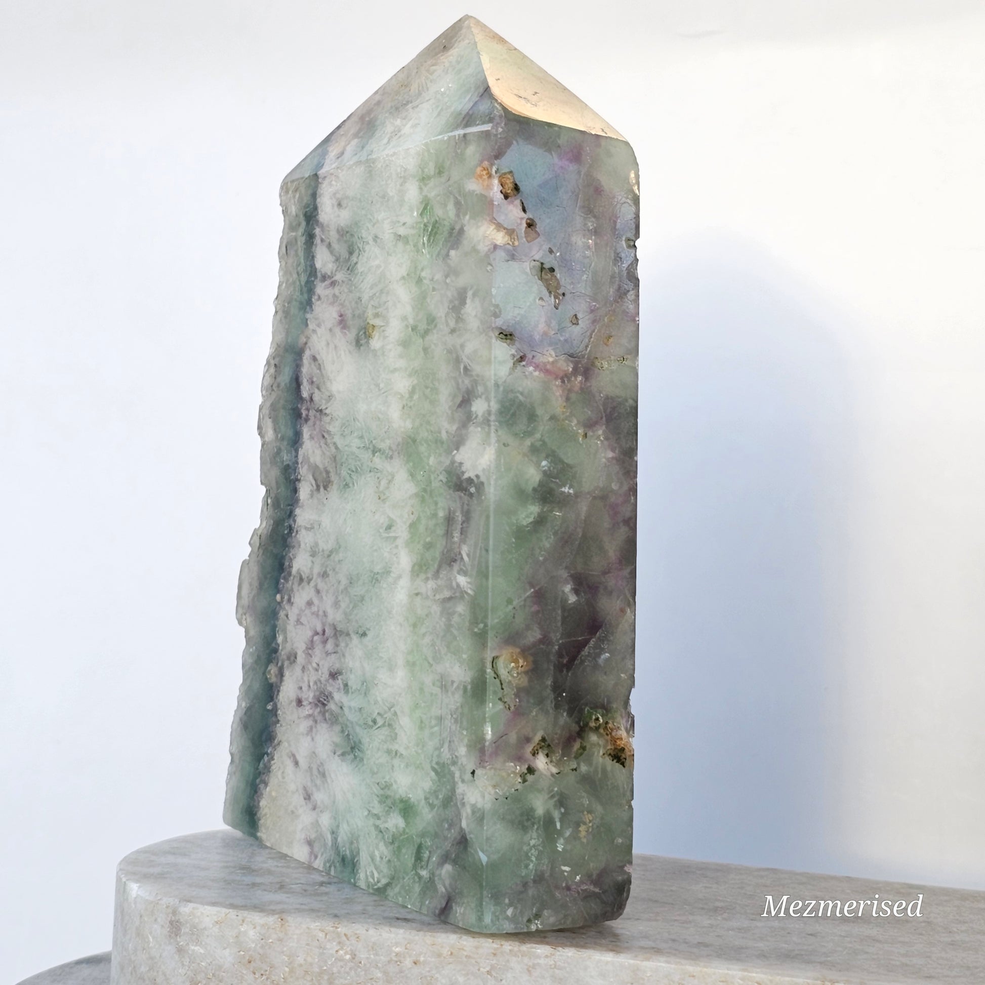 Angled view of Rainbow Feather Fluorite tower showing wide face with layered colour tones and natural internal formations.