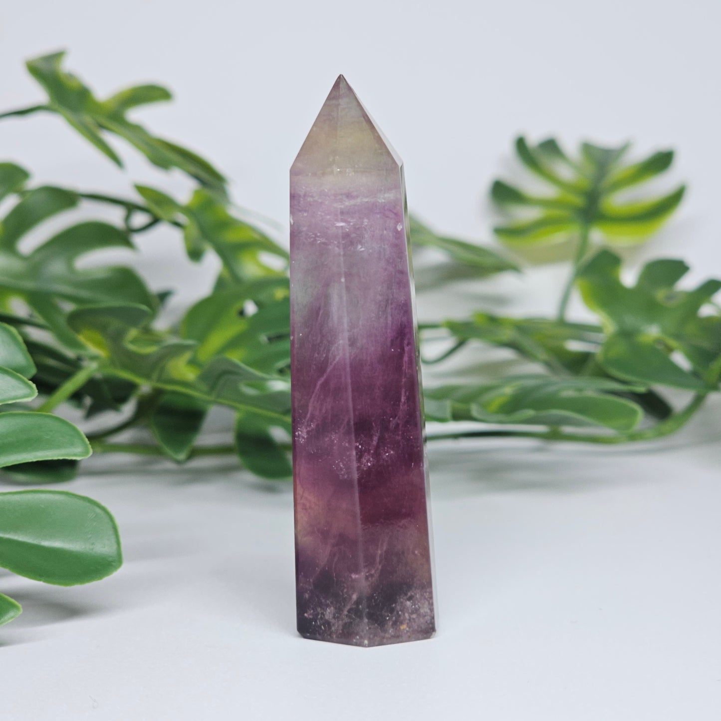 Fluorite crystal tower side profile showing layered banding with rich purple, soft green and yellow tones and polished finish