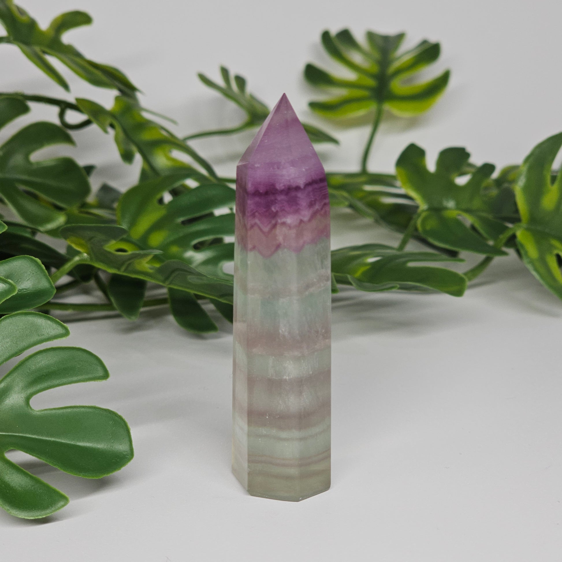 Fluorite crystal tower side profile showing layered banding with purple, green and yellow tones and polished finish