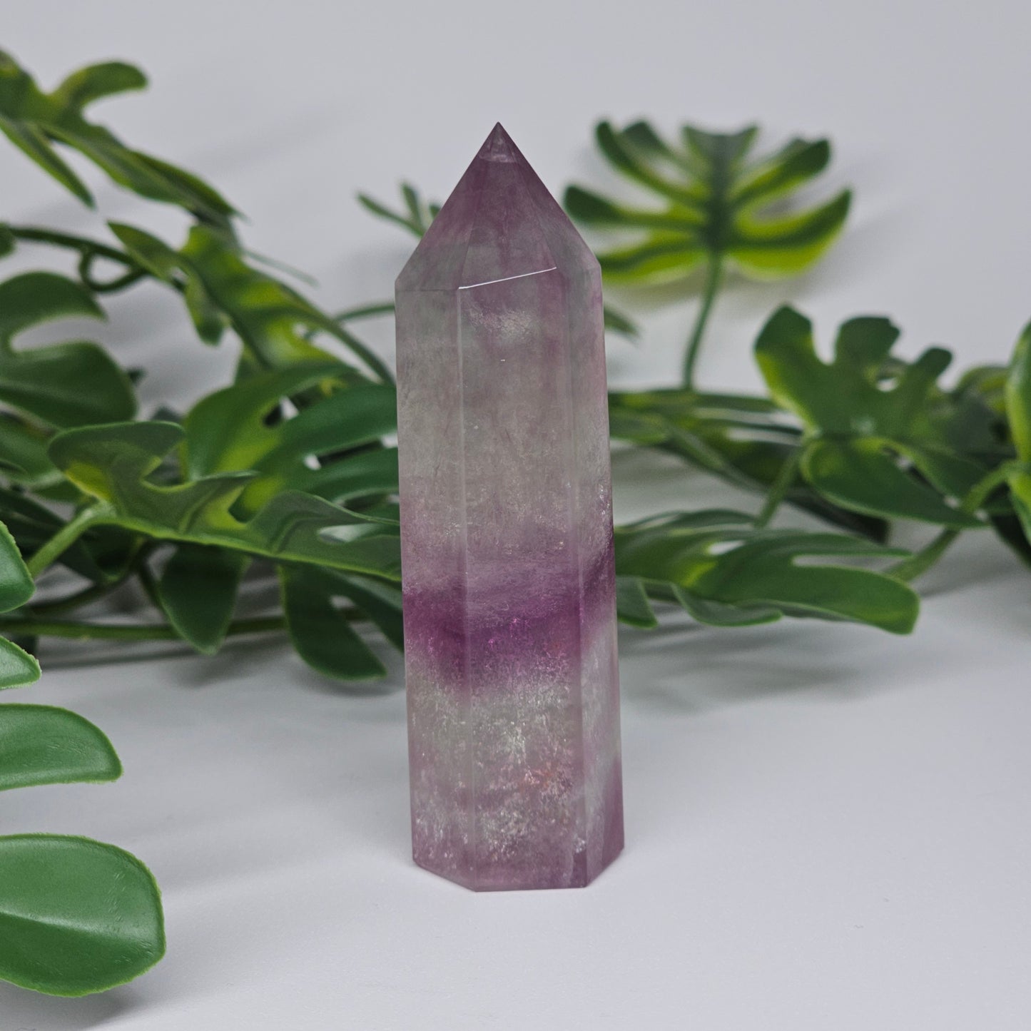 Fluorite crystal tower side profile showing layered banding with purple and green tones and polished finish