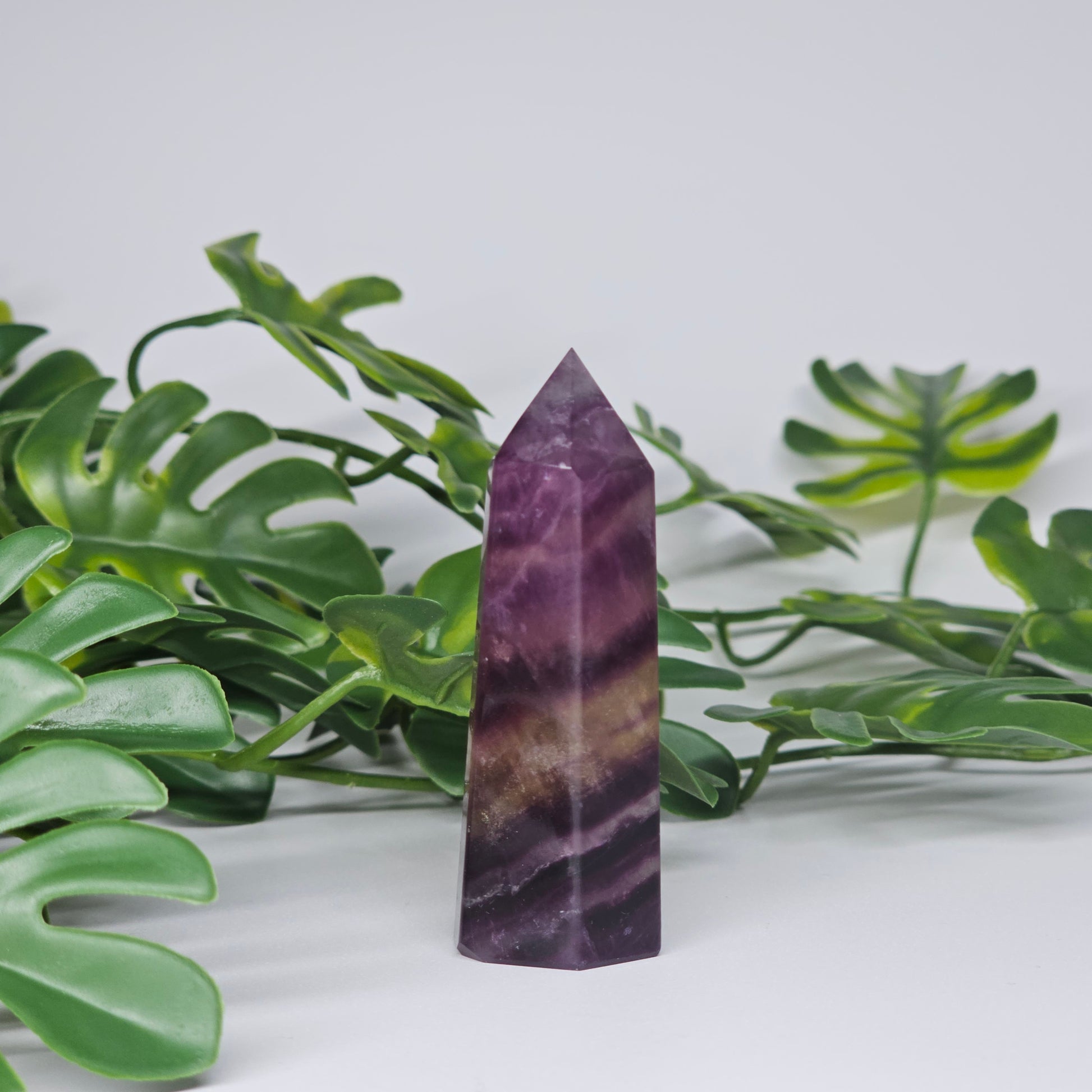 Fluorite crystal tower side profile showing layered banding with purple and yellow tones and polished finish