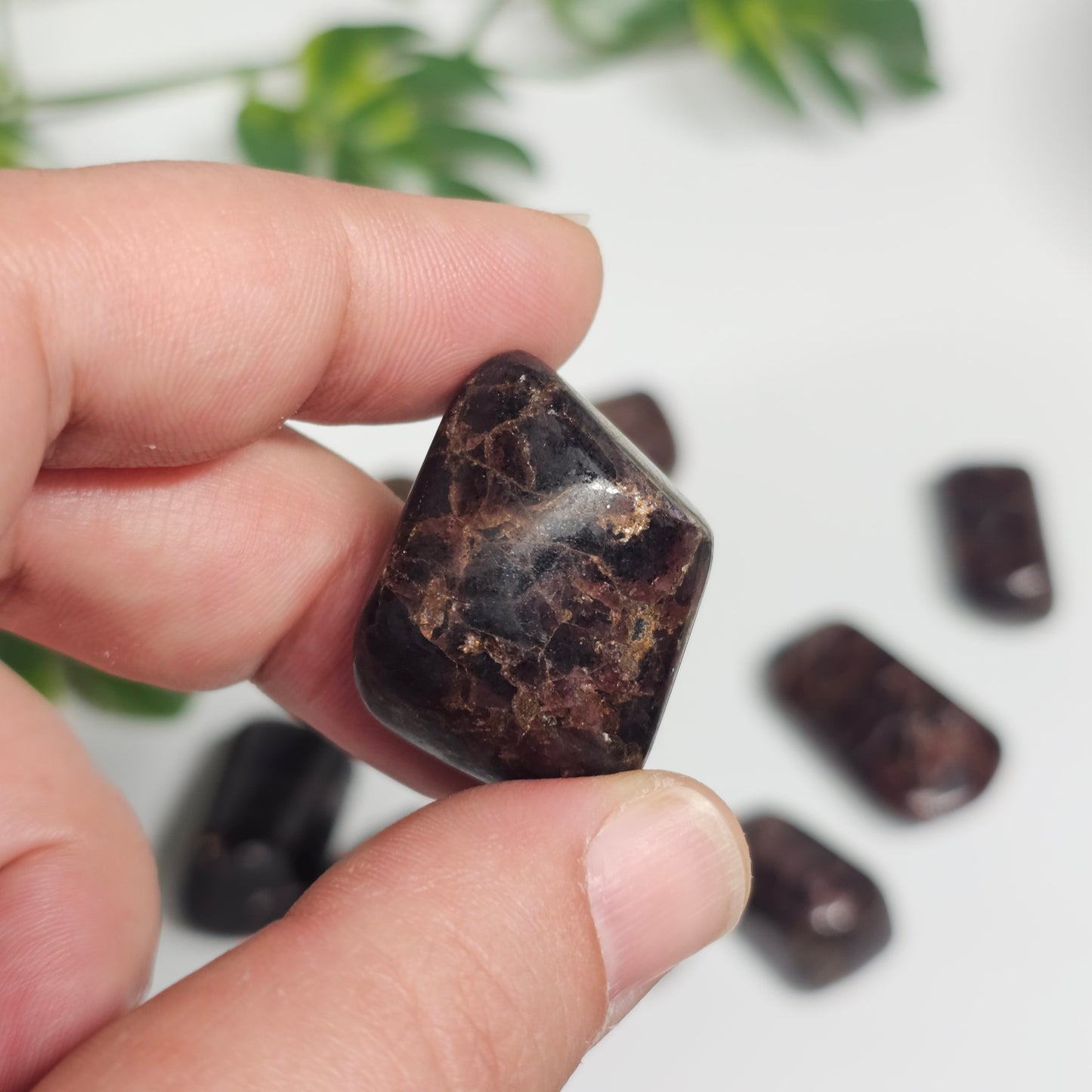 Close-up in-hand view of a Garnet tumble stone highlighting its rich colour saturation and smooth hand-polished finish.