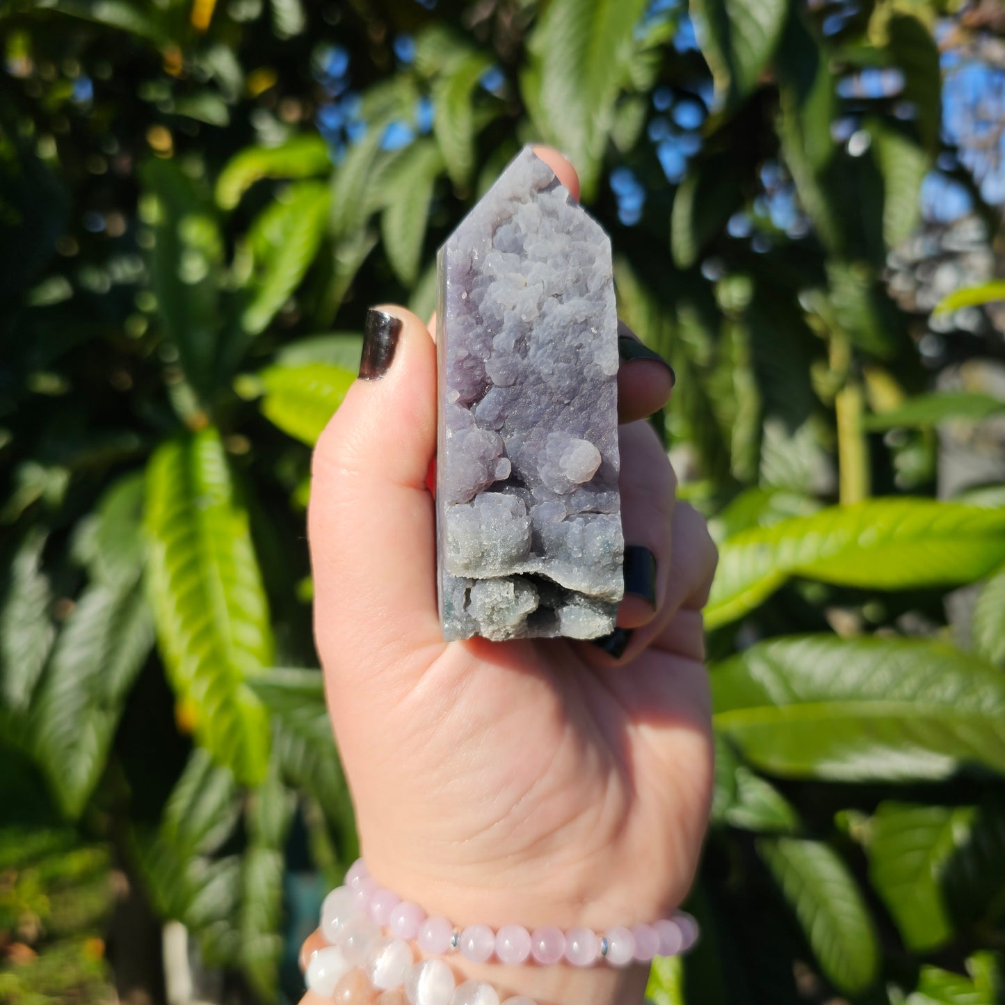 Grape Agate obelisk held in hand showing front face with soft purple ombre tones, natural matrix, and unique internal formations.
