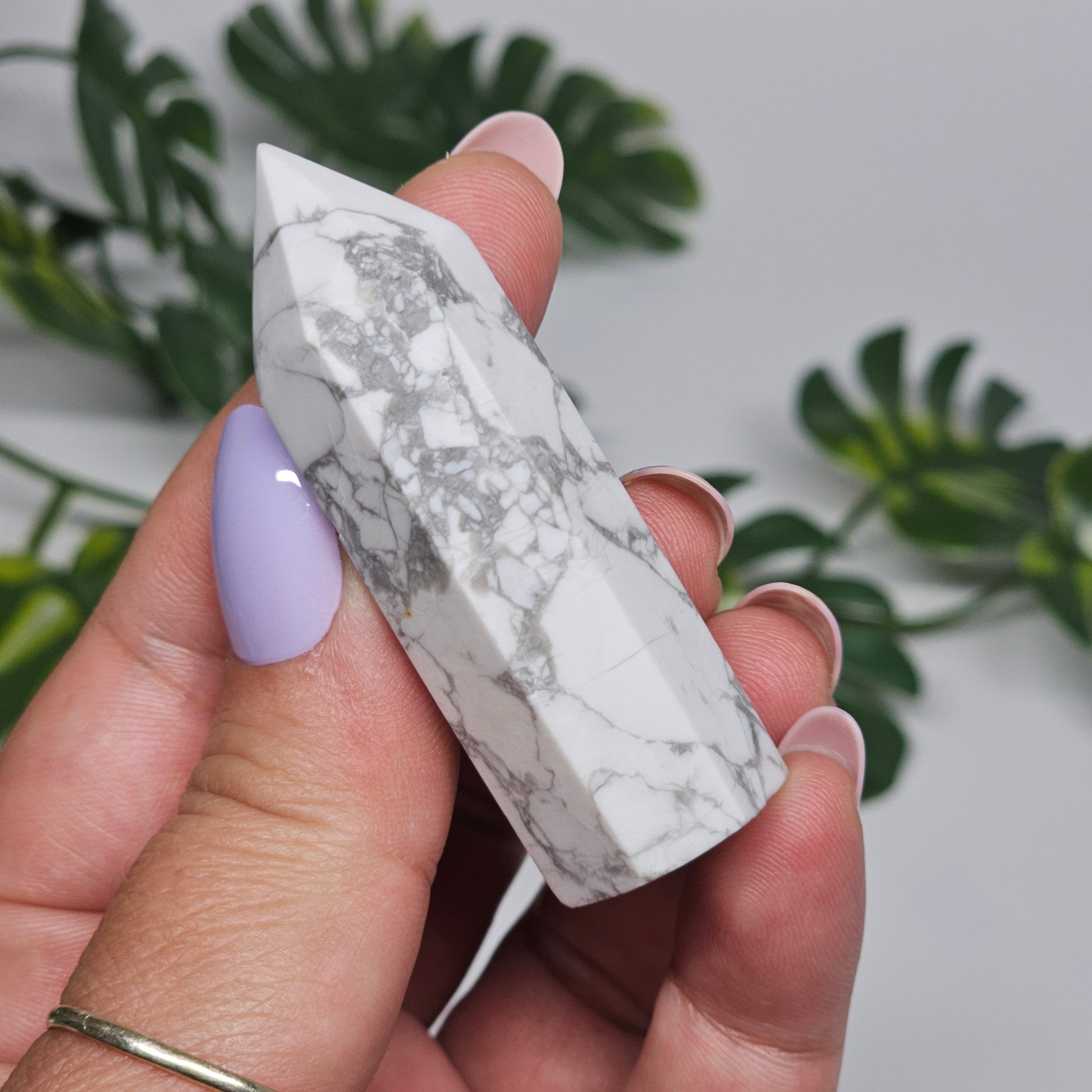 Howlite tower held in hand showing size and polished white stone.