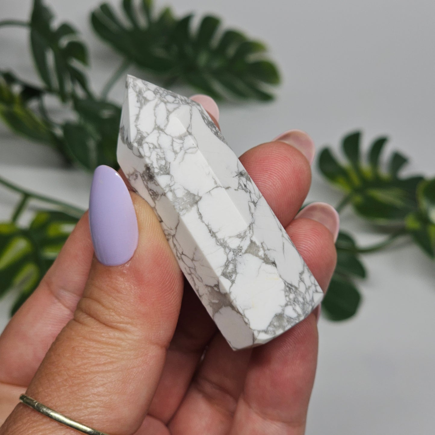 Howlite tower held in hand showing size and polished white stone.