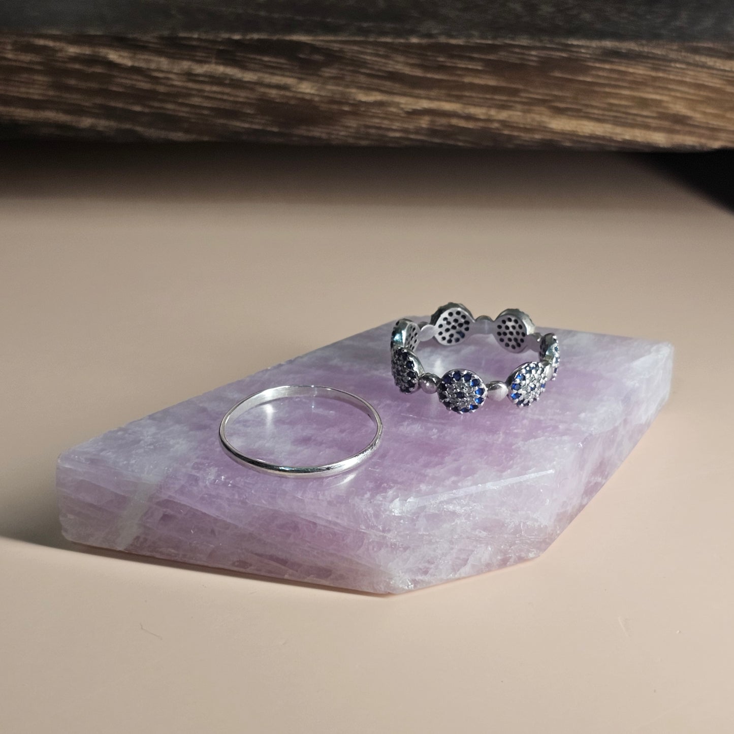 Kunzite slab styled with rings on top for display inspiration, highlighting its use as a jewellery photography prop.