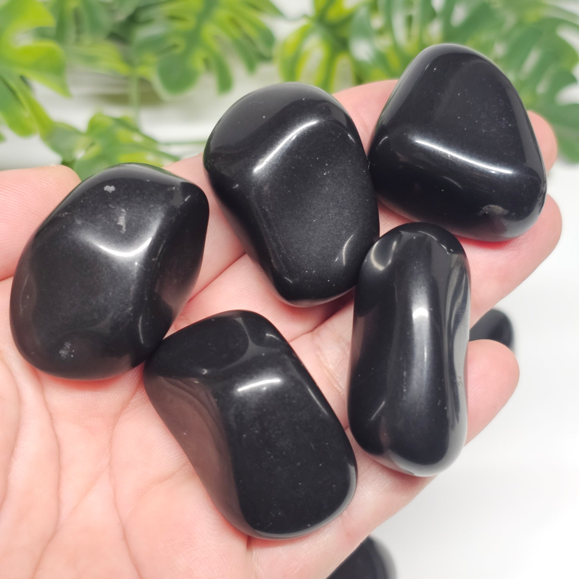 Large Black Tourmaline tumble stones held in hand, showcasing their deep black colour and strong grounding, protective energy.