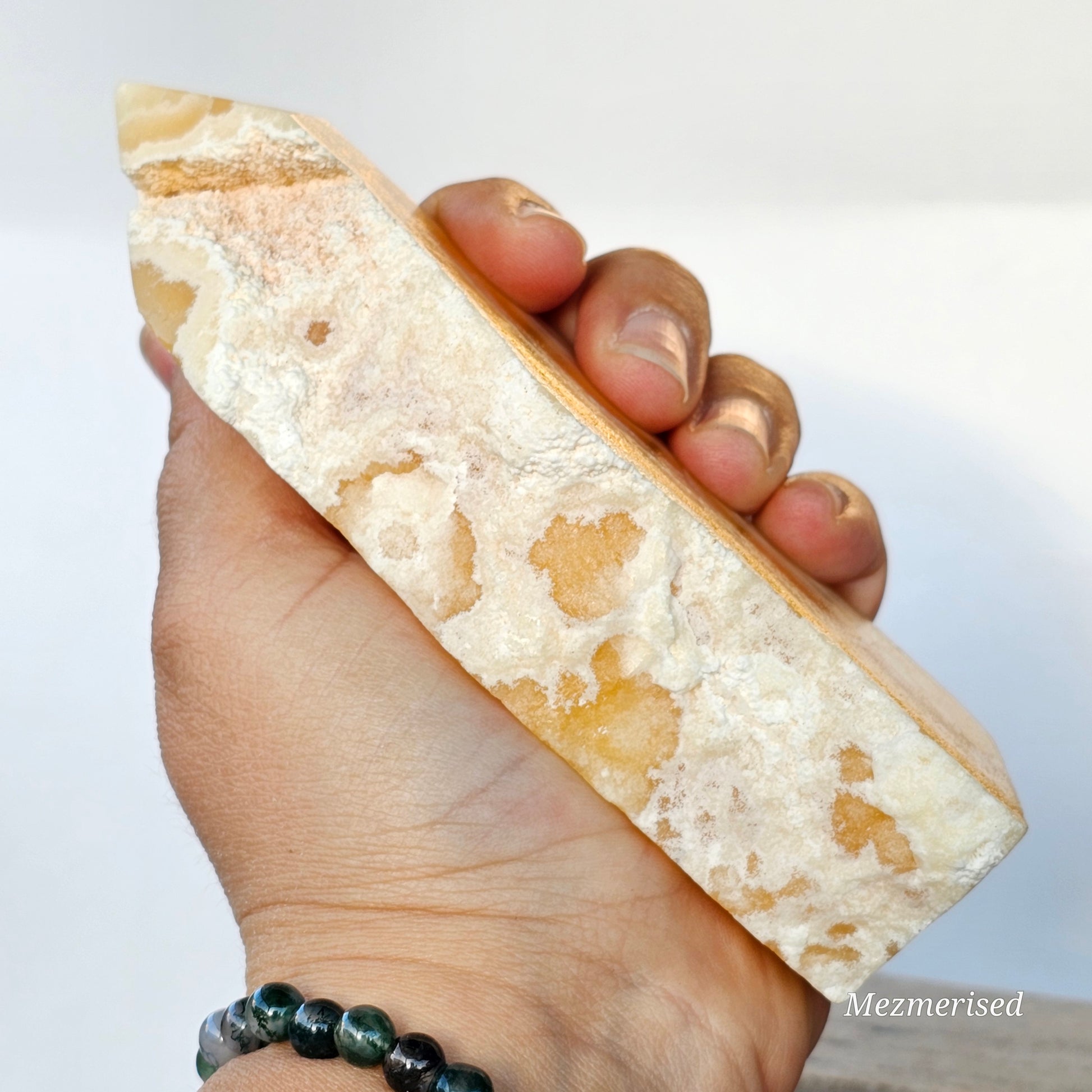 A hand-held photo demonstrating the 13.9cm scale of the tower while highlighting the earthy, matte white host rock texture.