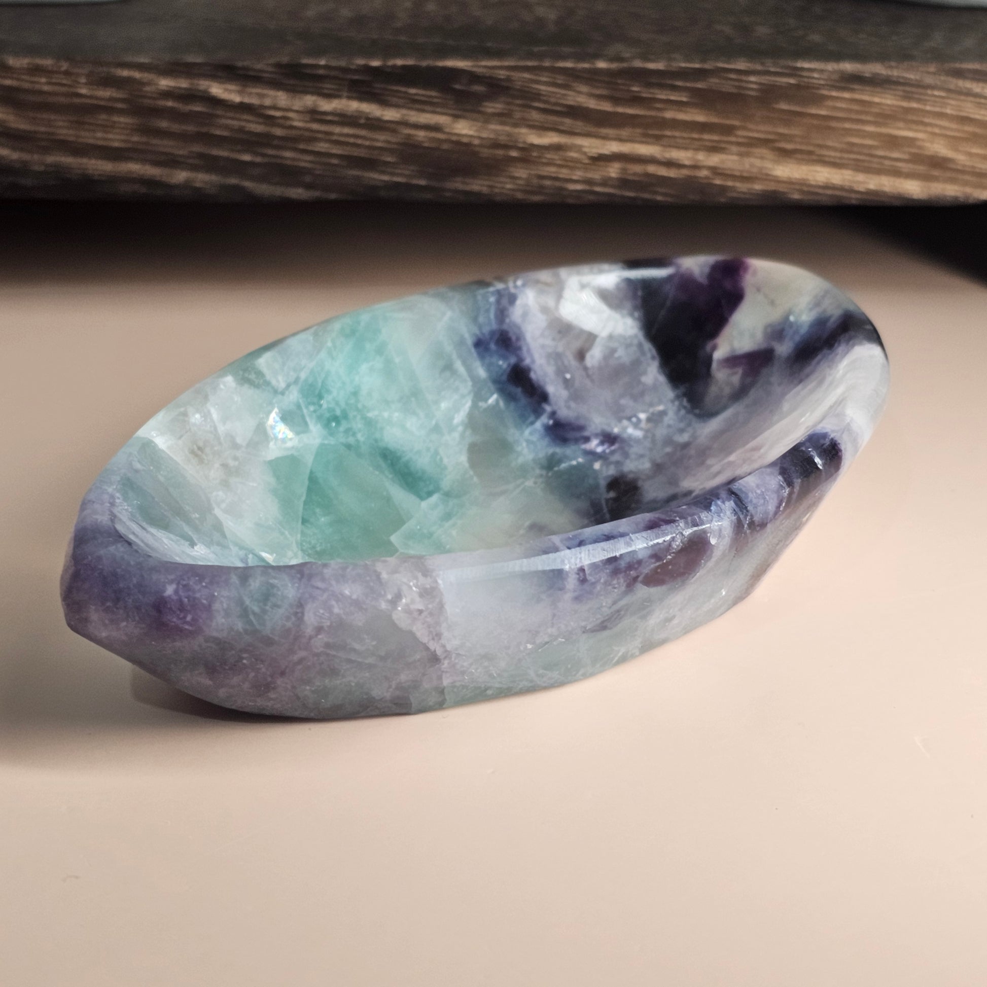 Side view of the marquise Fluorite bowl on a flat surface showing its tapered edges and smooth polished crystal finish.