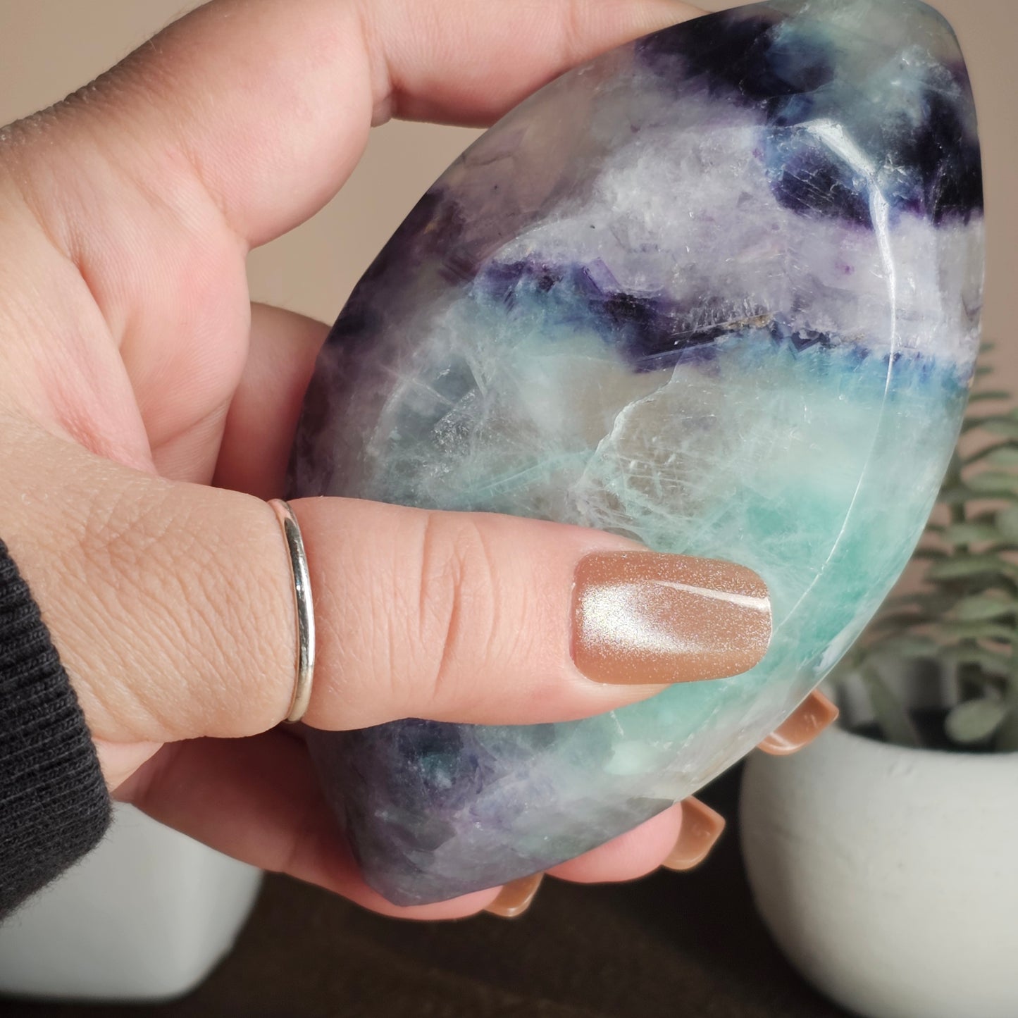 Underview of the marquise-shaped Fluorite bowl held in hand, highlighting its depth, translucency, and layered colour banding visible through the crystal.