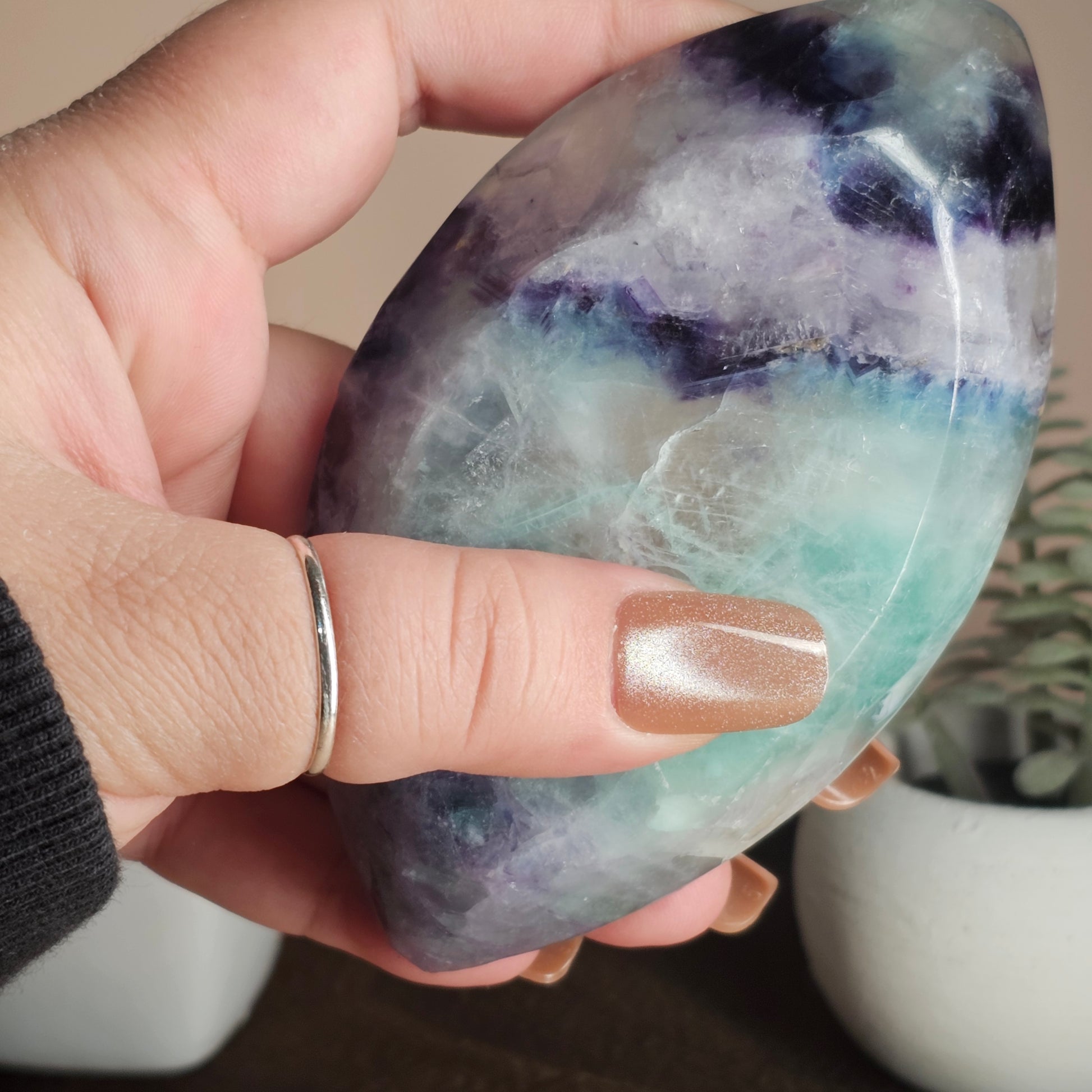 Underview of the marquise-shaped Fluorite bowl held in hand, highlighting its depth, translucency, and layered colour banding visible through the crystal.