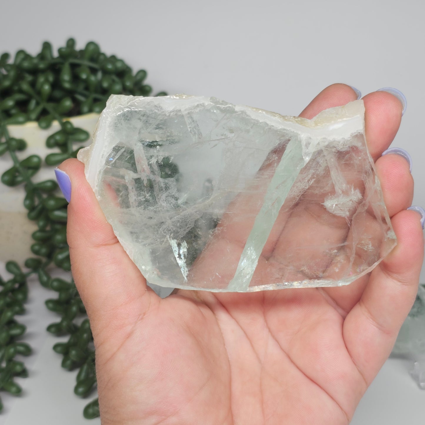 Medium Green Fluorite slab held in hand, showcasing glass-like transparency and natural green colouring.