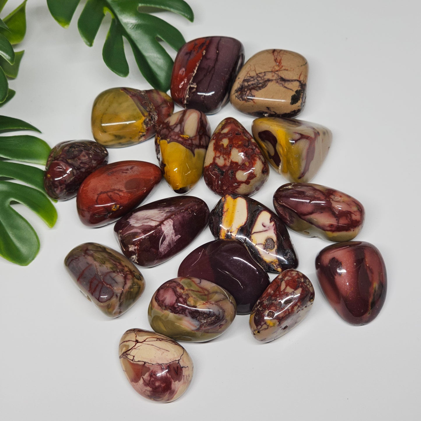 Mookaite Jasper tumble stones arranged on a flat surface, highlighting their grounding colour palette and unique organic patterns in natural light.