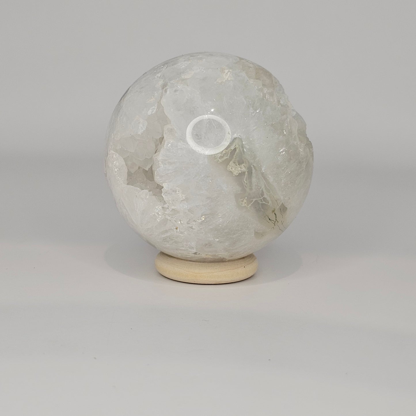 Alternate angle under studio lighting showing a different side of the sphere, highlighting the variation in moss inclusions and quartz structure.