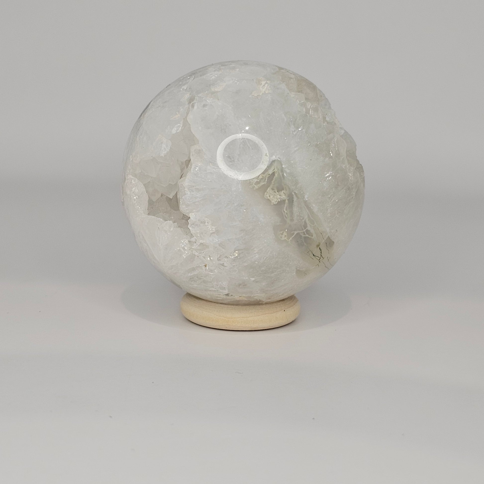 Alternate angle under studio lighting showing a different side of the sphere, highlighting the variation in moss inclusions and quartz structure.