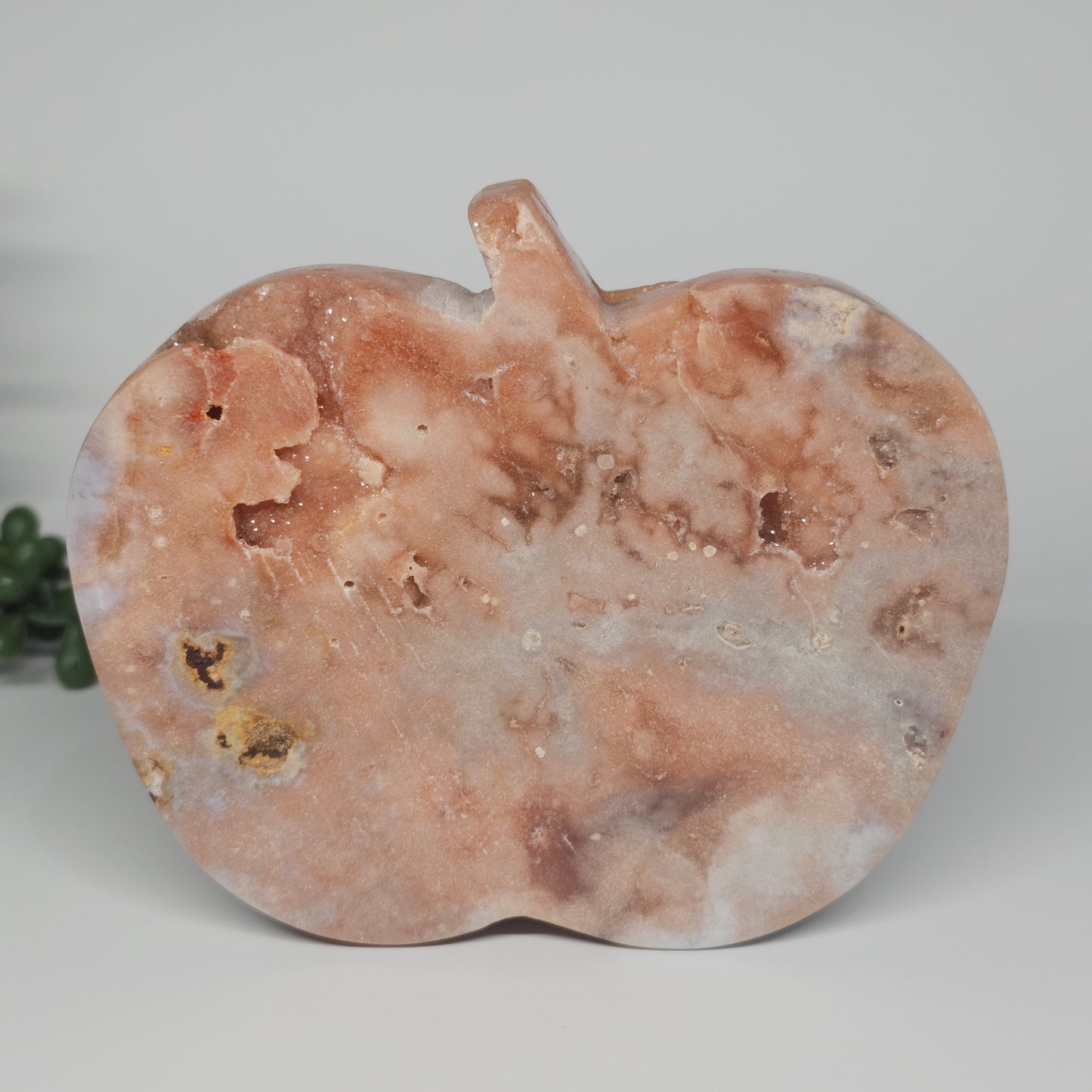 The reverse side of the carving showcasing solid pink tones and natural botryoidal formation embedded within the stone.