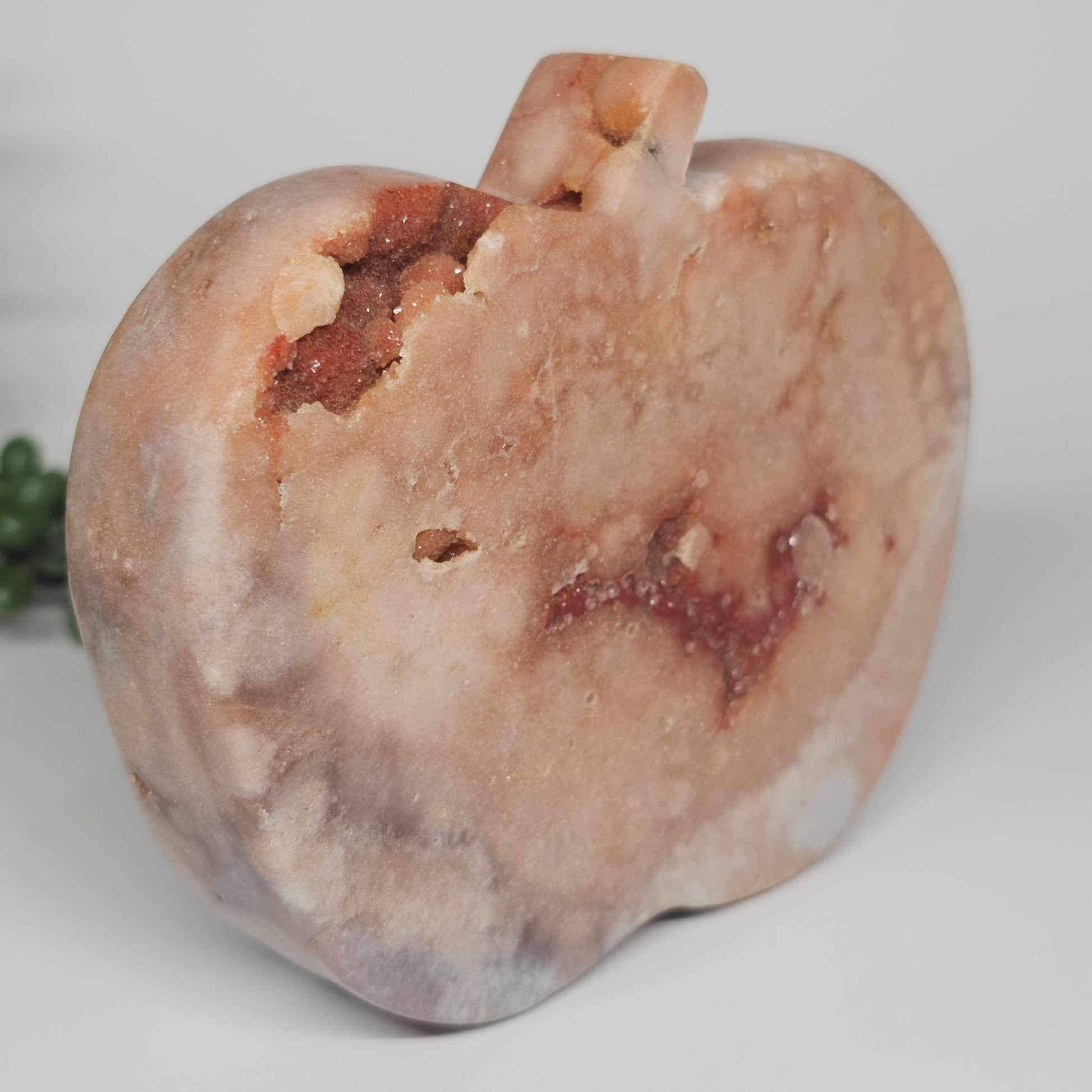 A side profile of the freestanding crystal apple showing its smooth, polished curves of the Pink Amethyst.