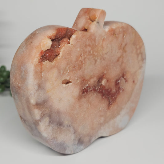 A side profile of the freestanding crystal apple showing its smooth, polished curves of the Pink Amethyst.