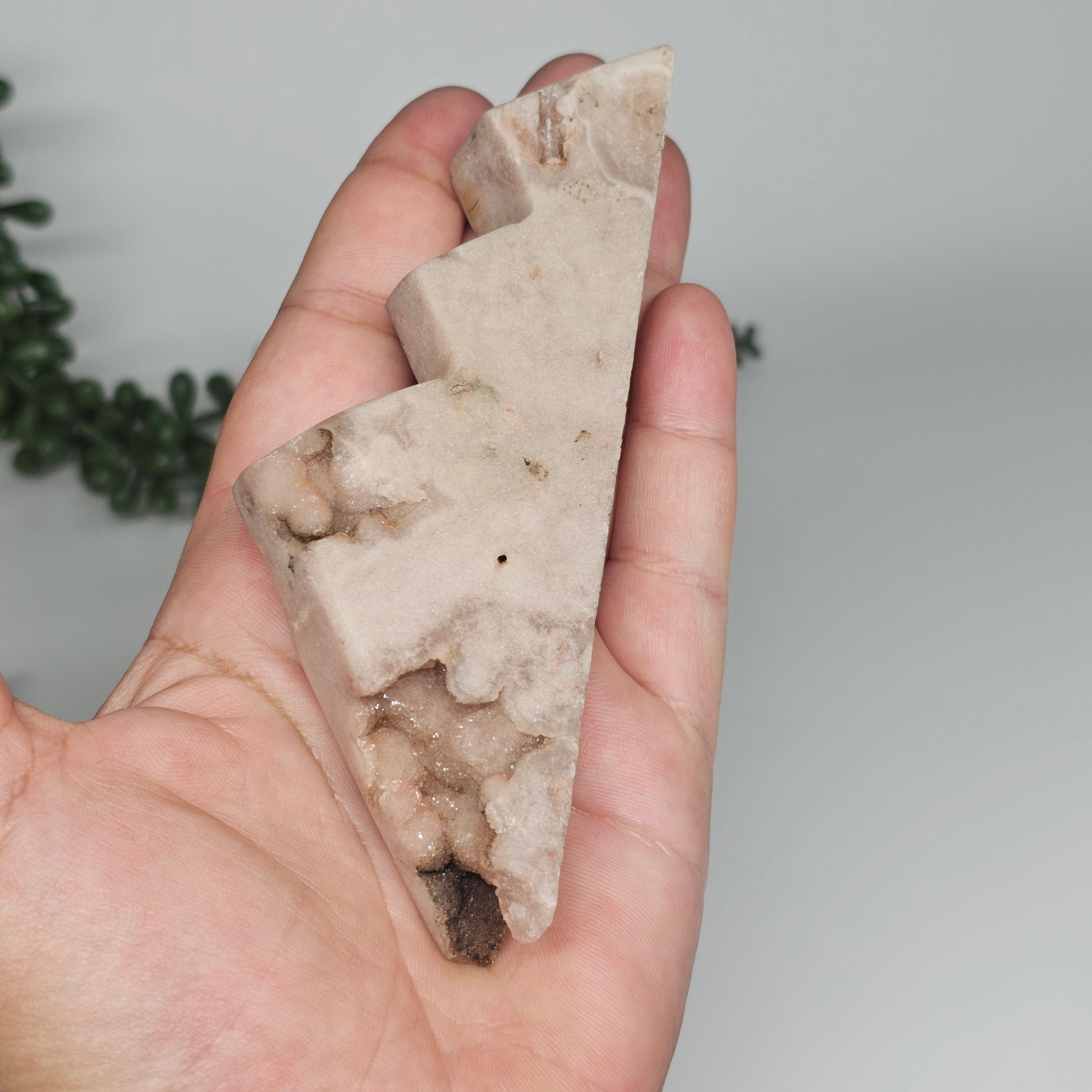 A hand-held photo demonstrating the petite size and soft mauvy tones of this 130g Brazilian carving.