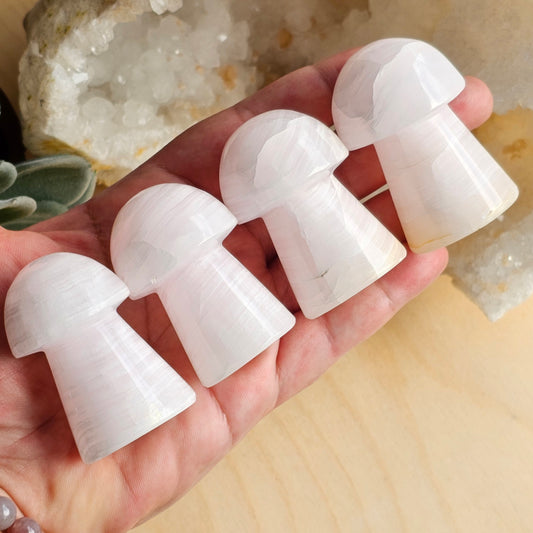 Pink Mangano Calcite mushrooms held in hand showing size, colour variation, and polished finish.